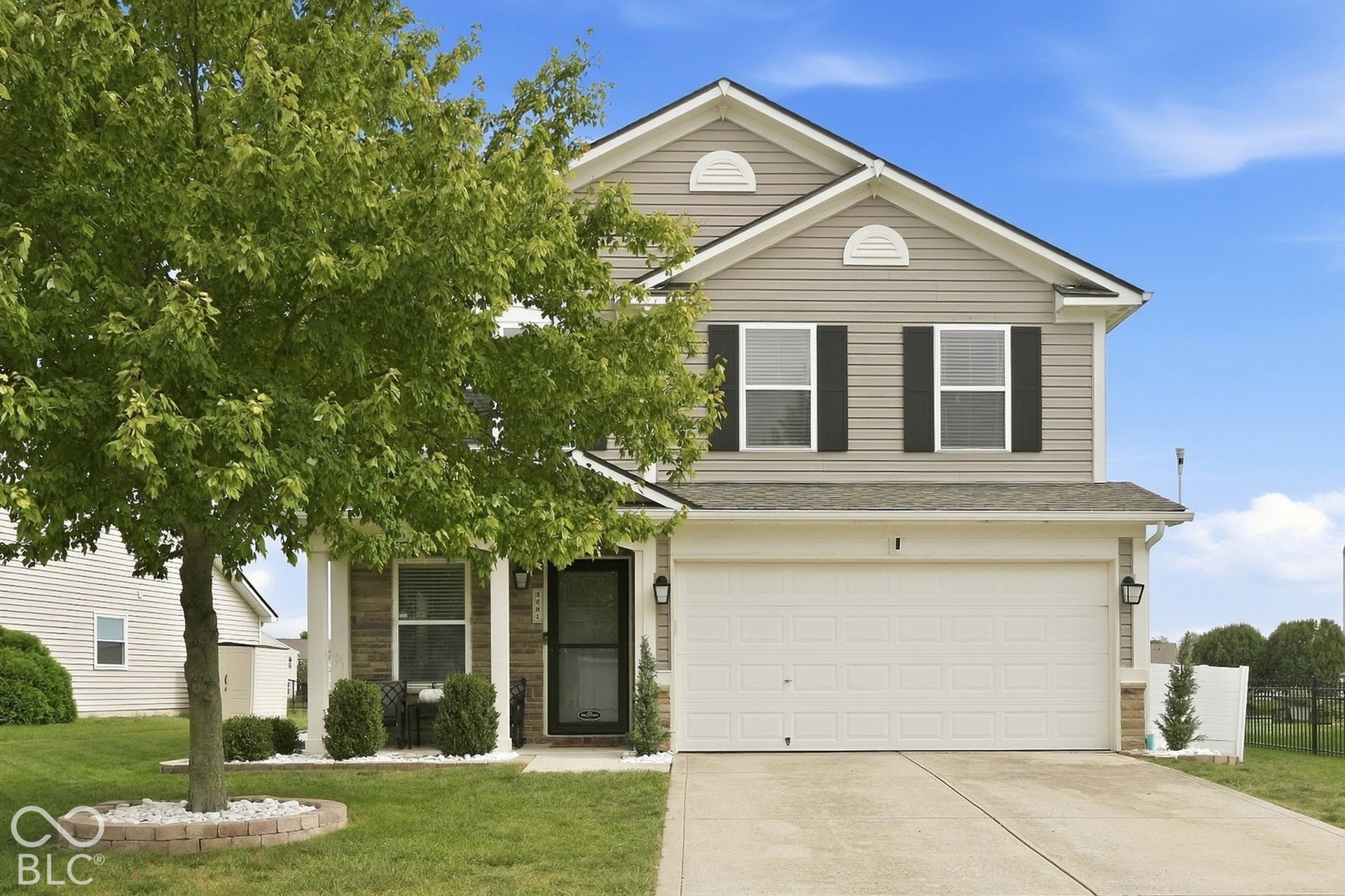 Two-story residence featuring light gray siding with dark shutters, a two-car garage, and a concrete driveway