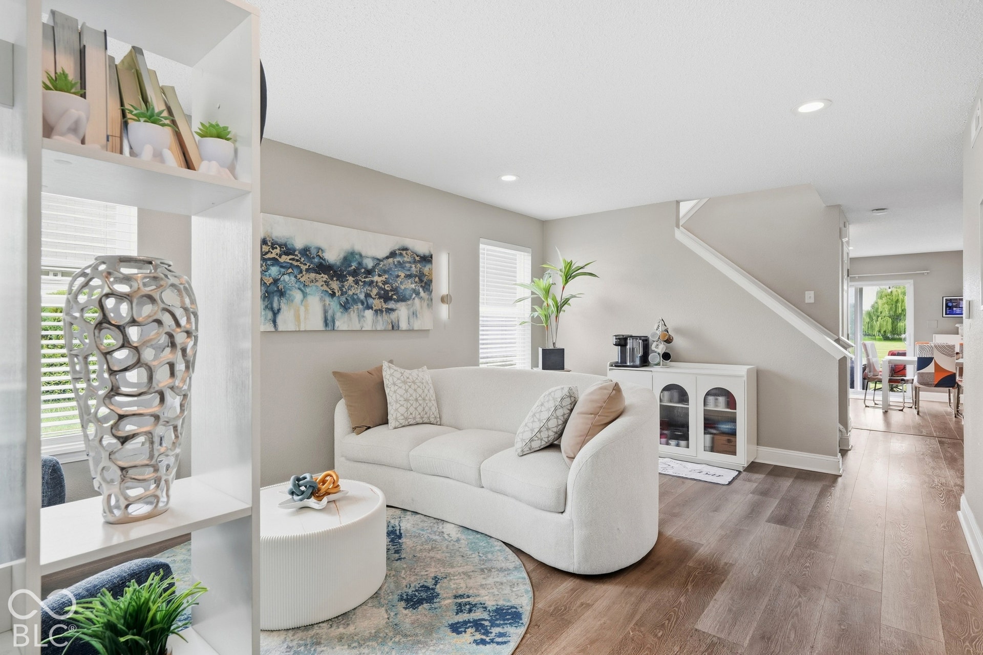 Open-concept living area featuring wood-finish flooring, recessed lighting, a built-in staircase, and a doorway to an exterior space