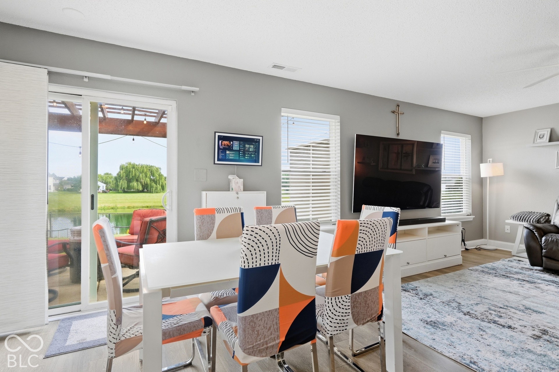 Sliding glass door opening to an outdoor patio with a pergola, offering water views