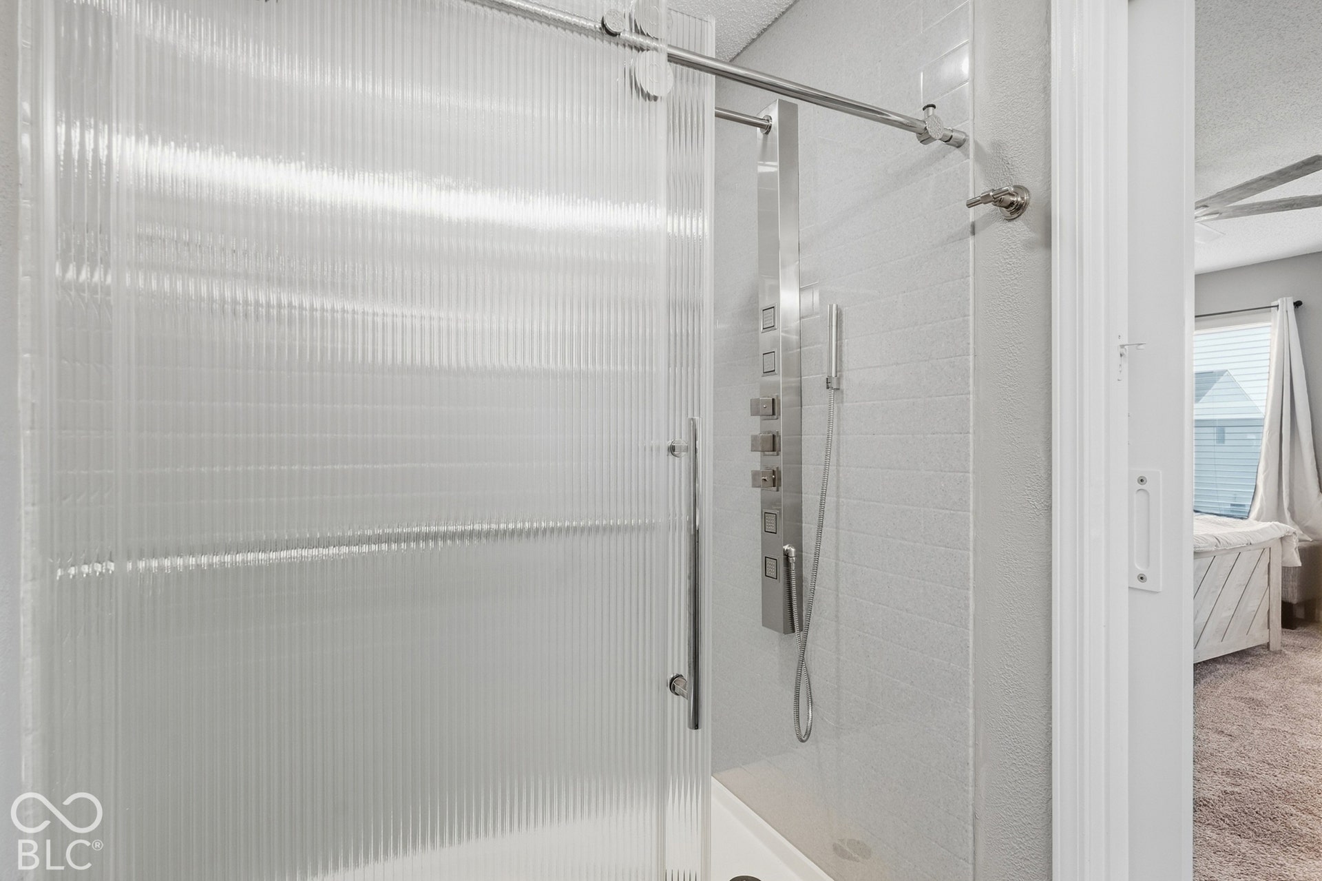Oversized walk-in shower with floor-to-ceiling Onyx surround, fluted glass enclosure, multi-shelf and multi-function shower system