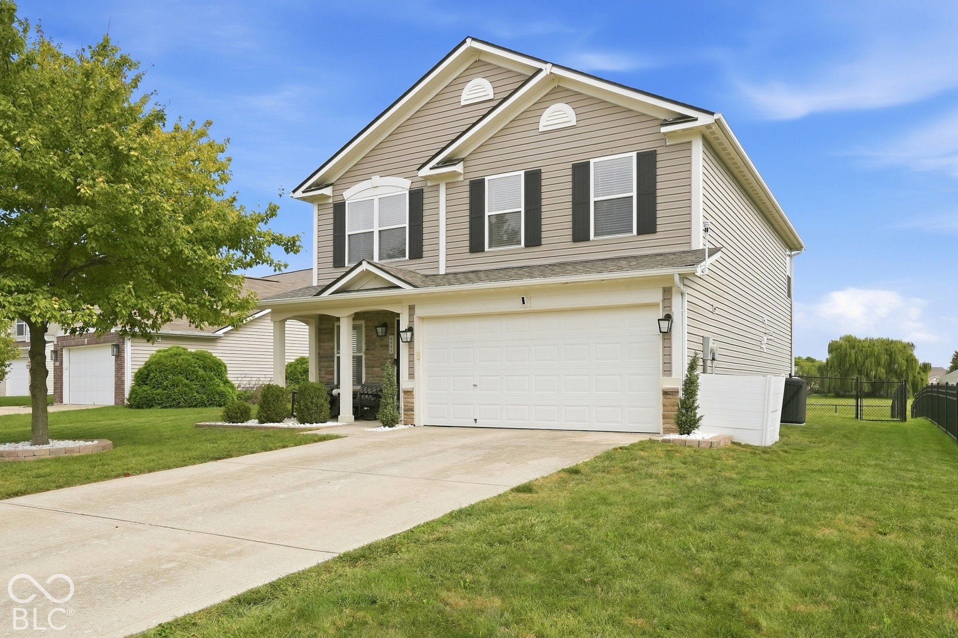 Two-story residence featuring siding exterior, an attached two-car garage, a covered front porch, and a paved driveway