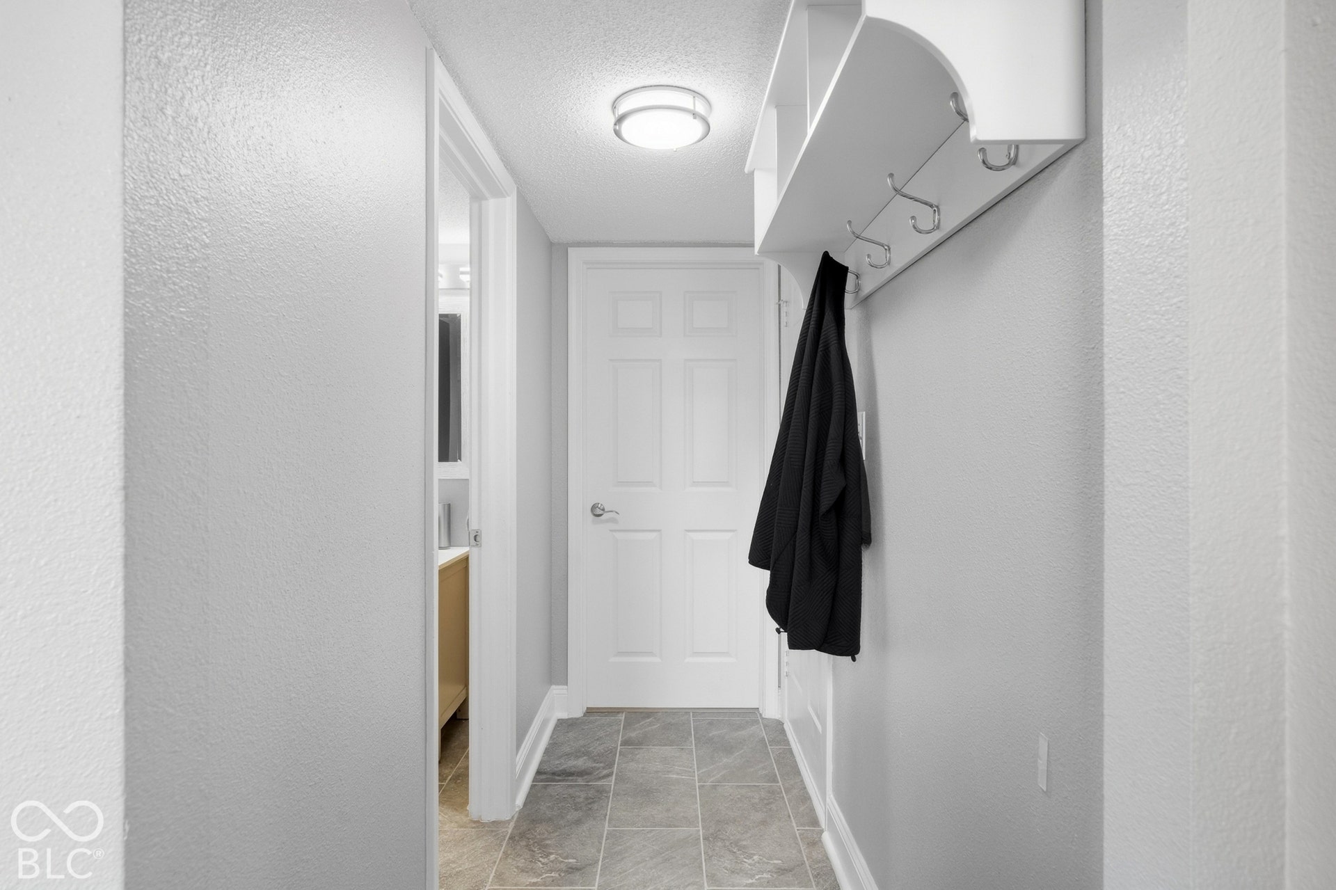 Hallway featuring tiled flooring, recessed ceiling light, and built-in coat rack with shelving