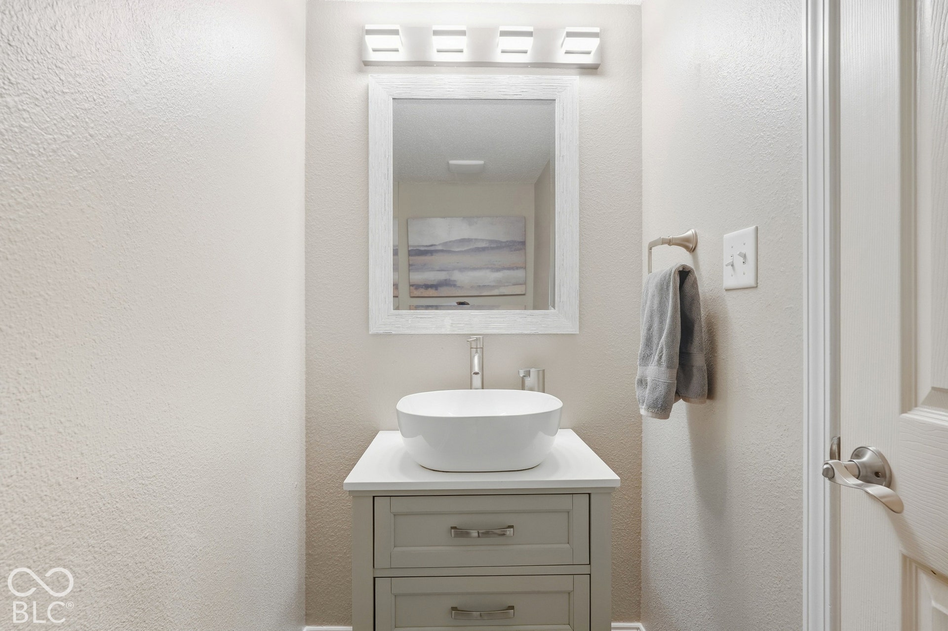 Pedestal vanity with a vessel sink, square framed mirror, and modern wall-mounted lighting