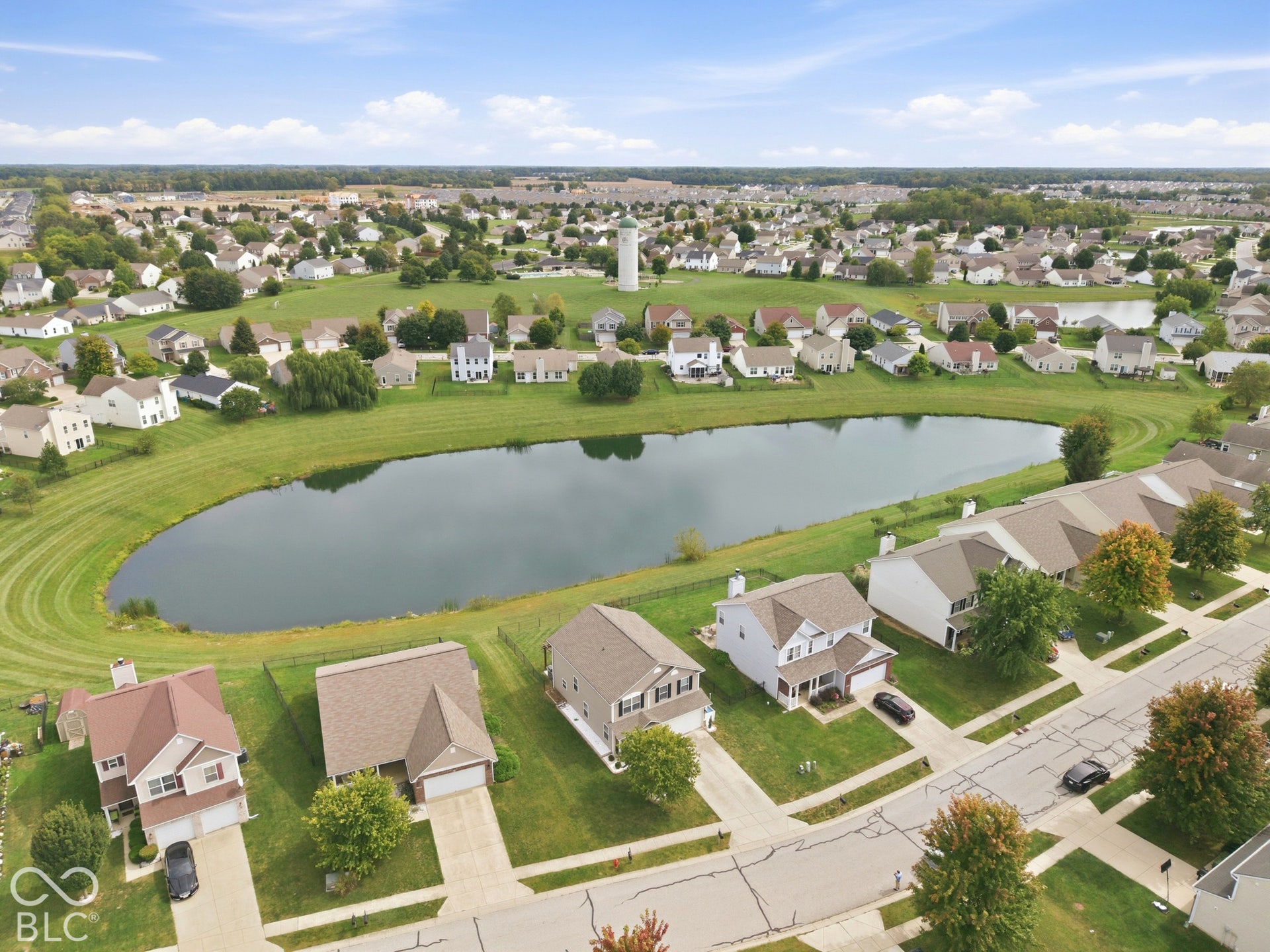 Neighborhood setting featuring a central pond, surrounding green spaces, and residential homes with established landscaping
