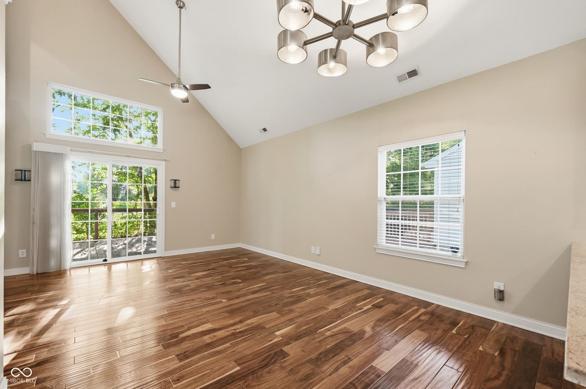 2743 Rylee Court, Greenwood, IN 46143 Vaulted ceilings with a modern chandelier, acacia hardwood floors, and sliding glass doors