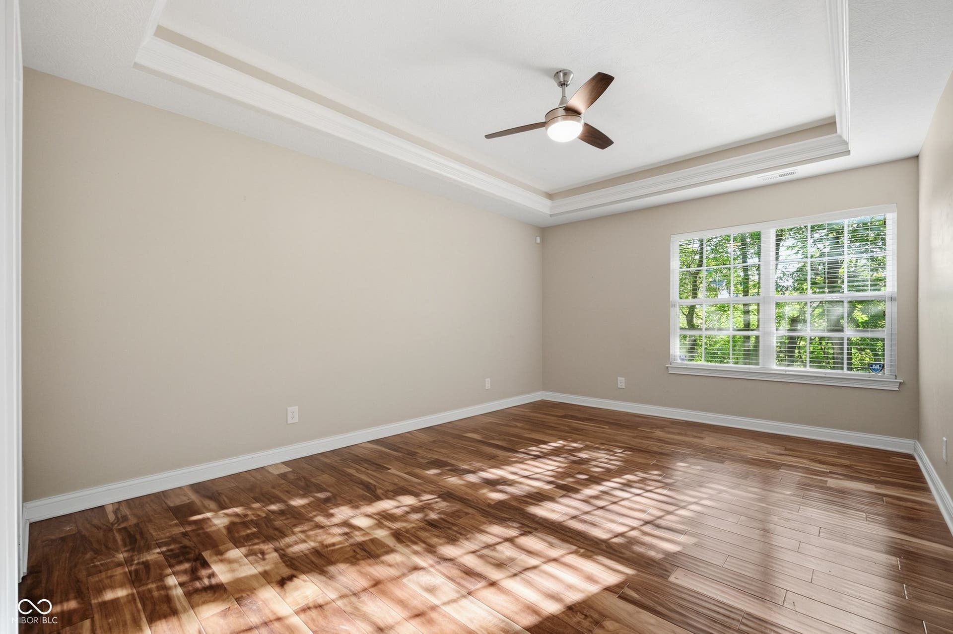2743 Rylee Court, Greenwood, IN 46143 Recessed lighted tray ceiling with crown molding, ceiling fan, acacia wood flooring, and a large window