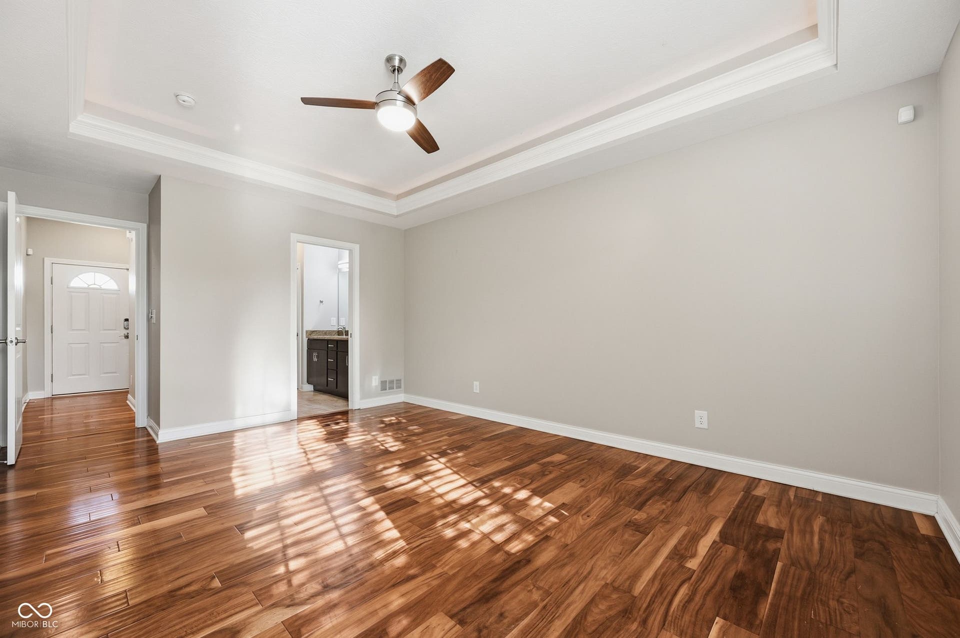 2743 Rylee Court, Greenwood, IN 46143 Acacia hardwood flooring, lighted tray ceiling with crown molding, ceiling fan with integrated lighting, neutral wall tones, and white trim