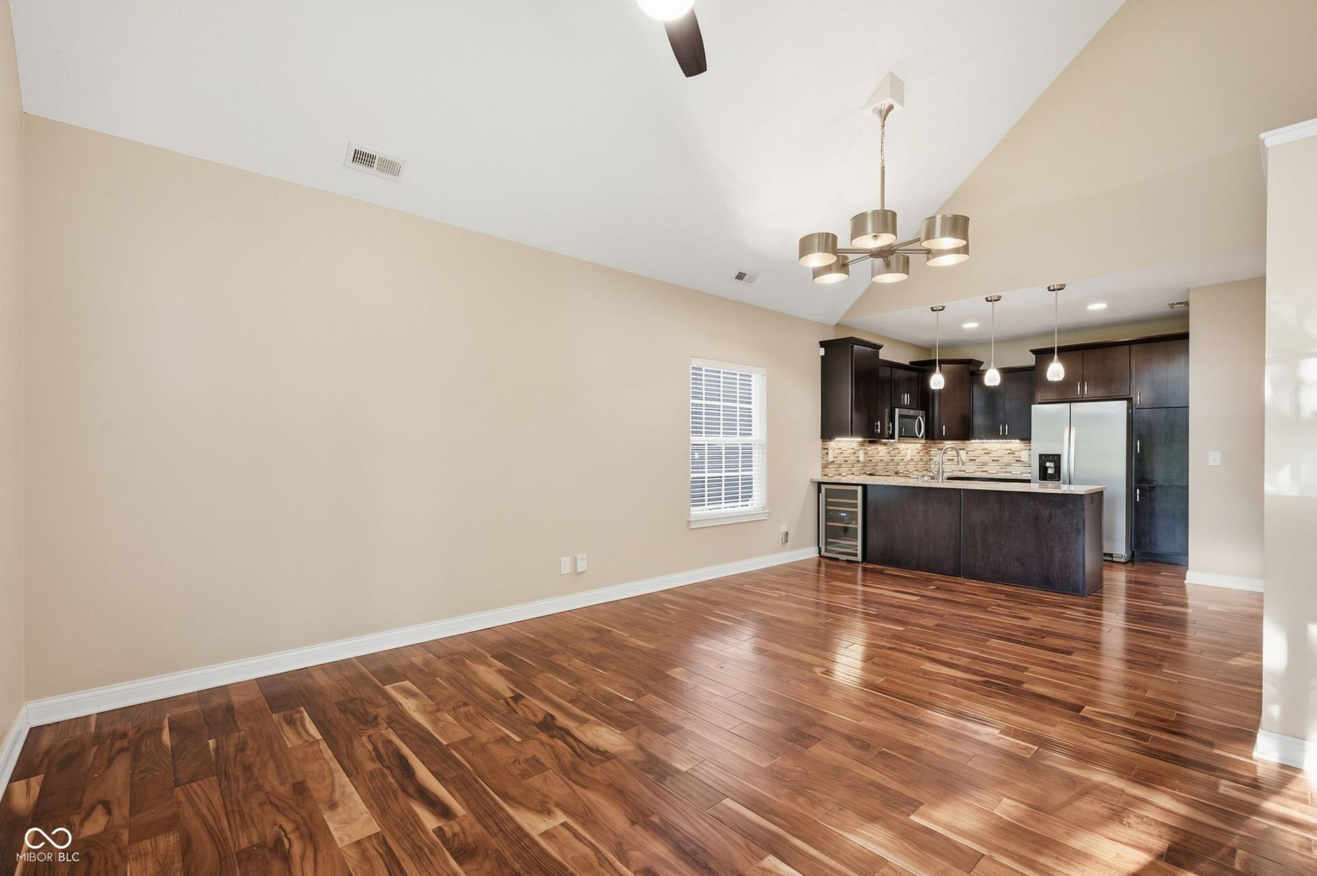 2743 Rylee Court, Greenwood, IN 46143 Open-concept living space featuring acacia hardwood floors, vaulted ceilings, and a kitchen with dark wood cabinetry and stainless steel appliances