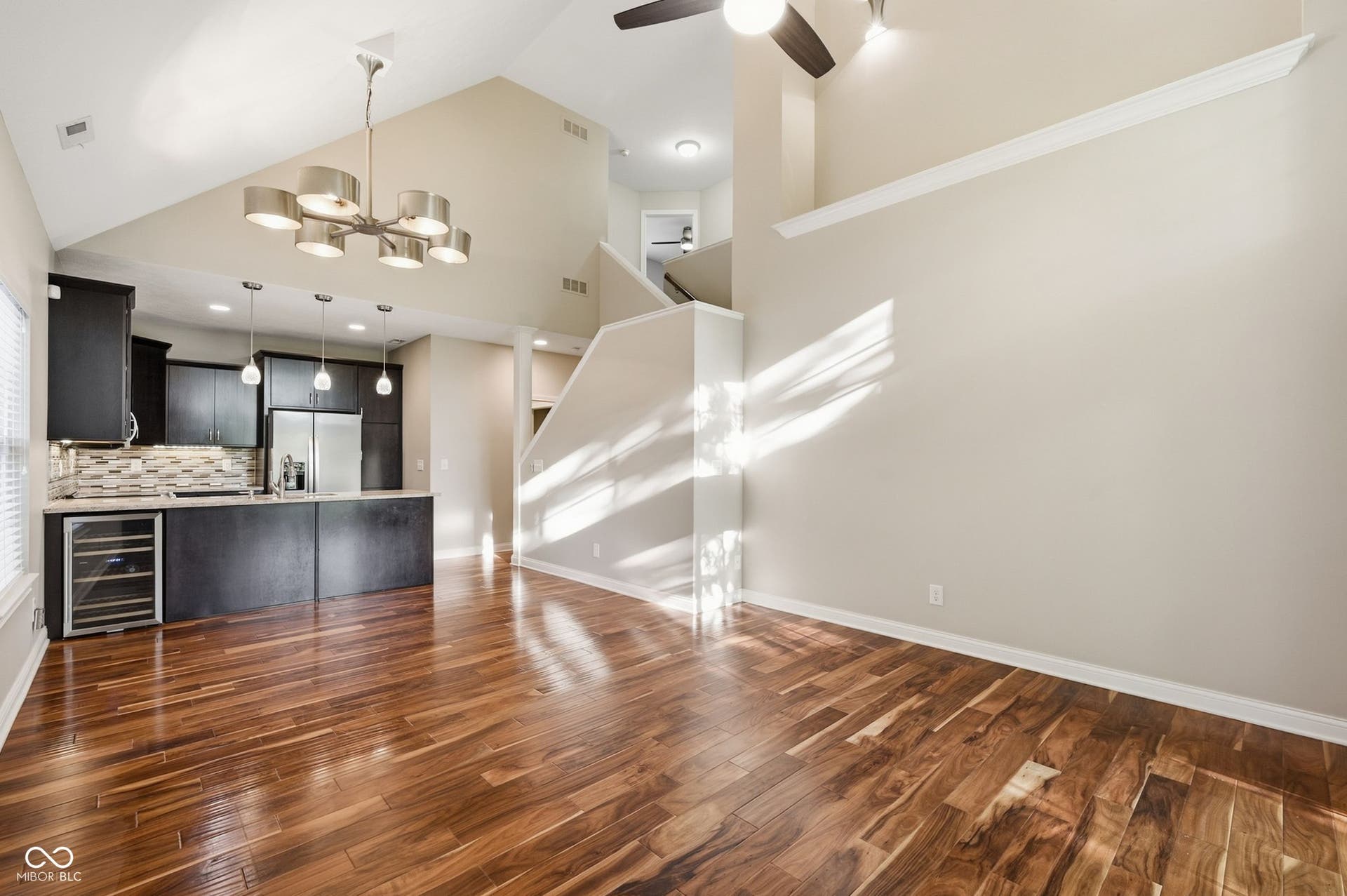 2743 Rylee Court, Greenwood, IN 46143 Vaulted ceiling, acacia hardwood floors. dark wood cabinetry, built-in wine refrigerator, and a contemporary chandelier