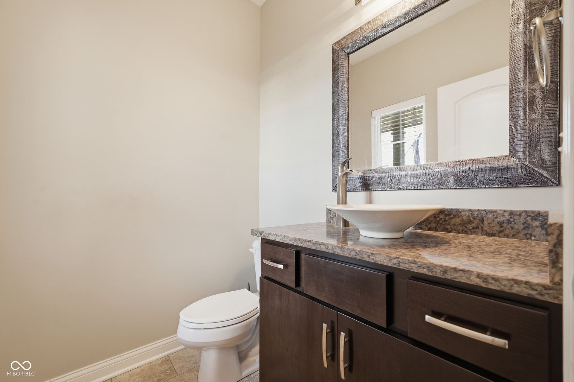 2743 Rylee Court, Greenwood, IN 46143 Dark wood-finish vanity with drawer and cabinet storage, granite countertop, vessel sink, and an ornamental framed mirror