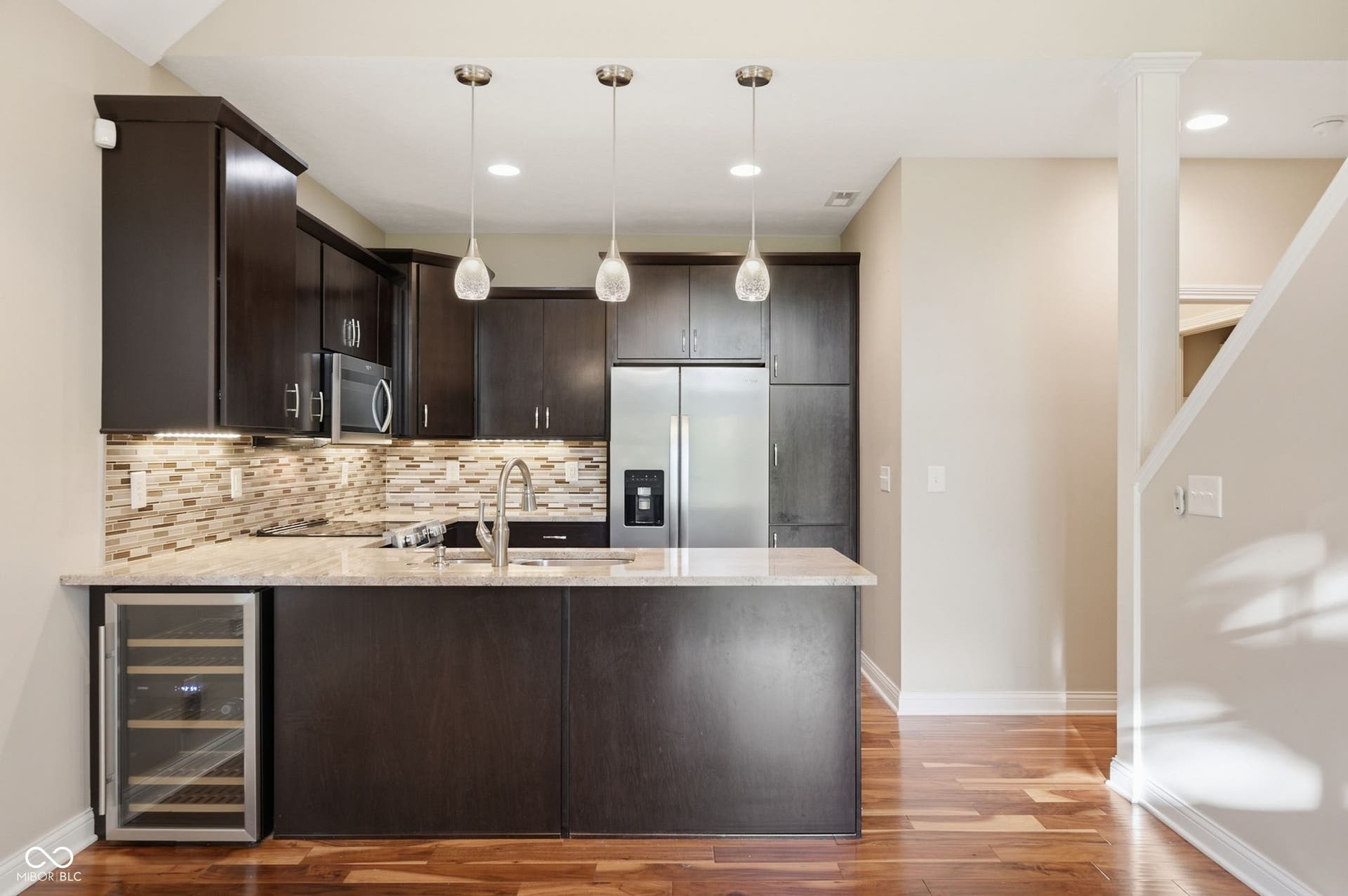 2743 Rylee Court, Greenwood, IN 46143 Kitchen featuring dark wood cabinetry, stainless steel appliances, light-toned granite countertops, tile backsplash, and three pendant lights