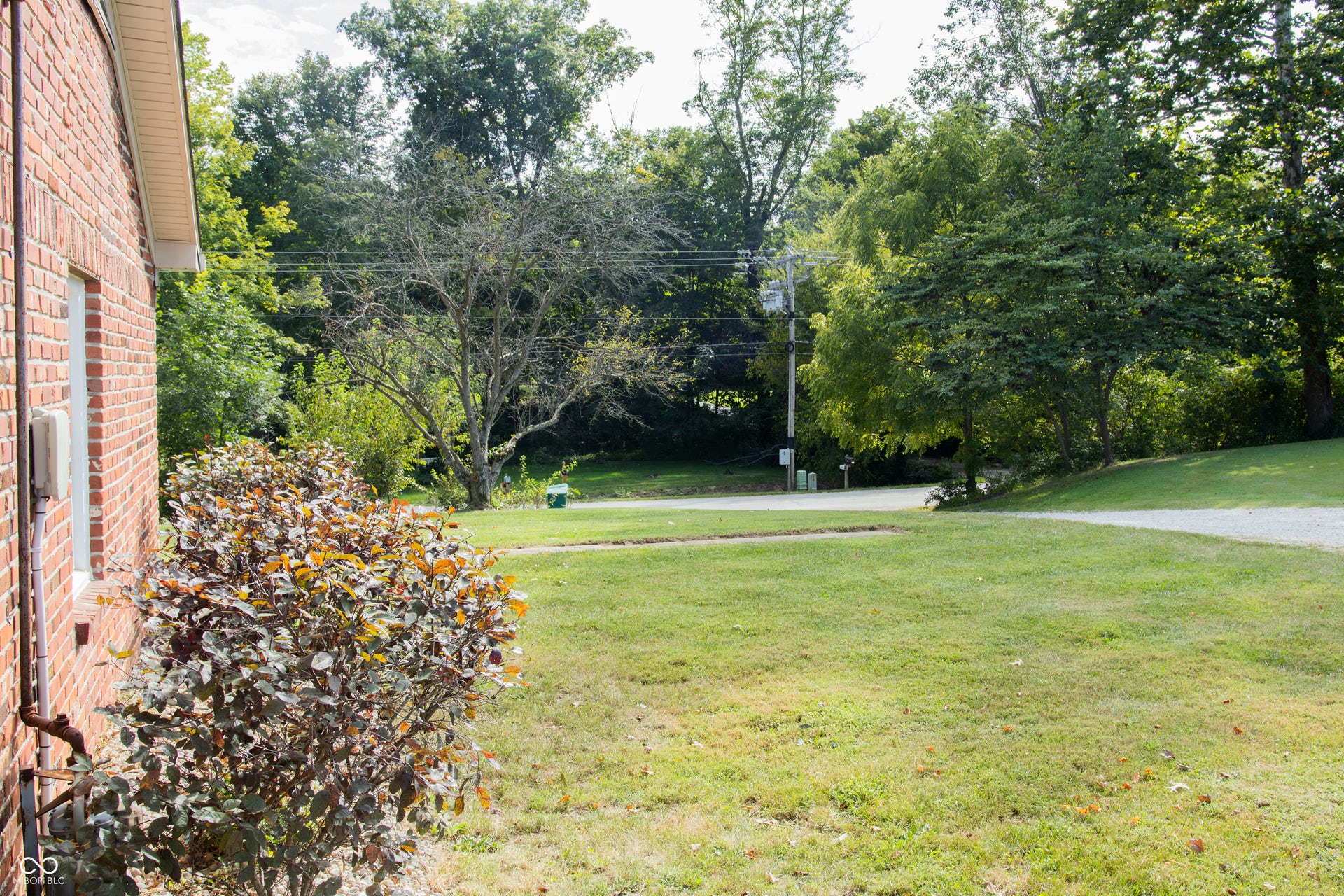 Brick exterior with white soffit, established landscaping, and a gravel driveway
