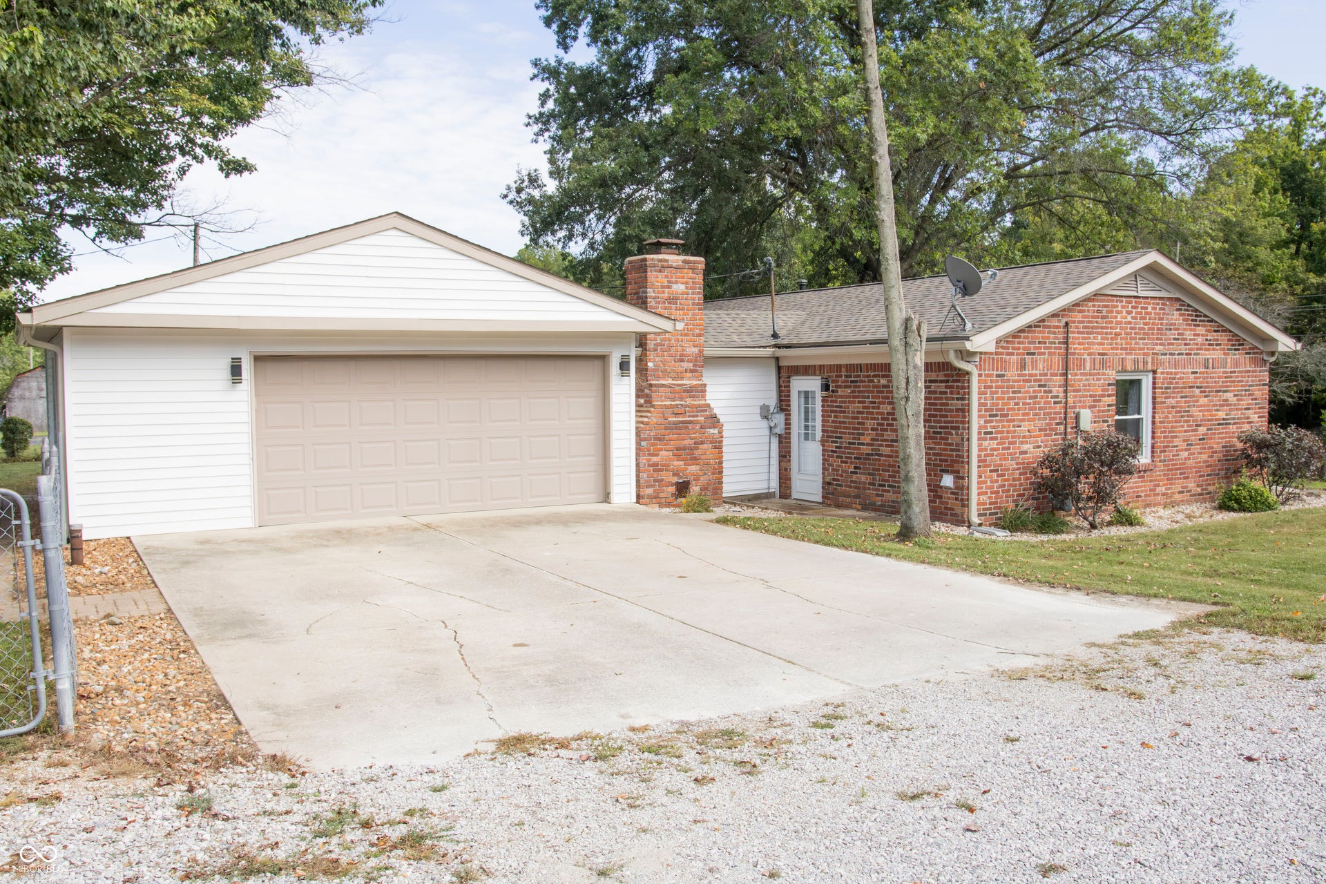 Attached two-car garage with overhead door, exterior wall lighting, and concrete driveway