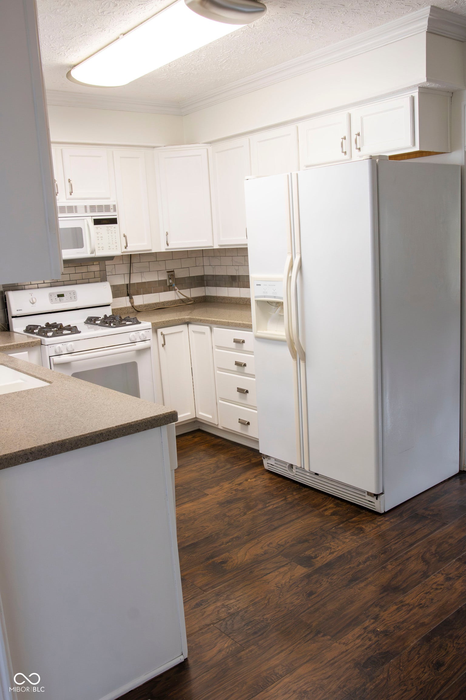 Kitchen featuring white cabinetry, dark wood-finish flooring, and light-toned countertops