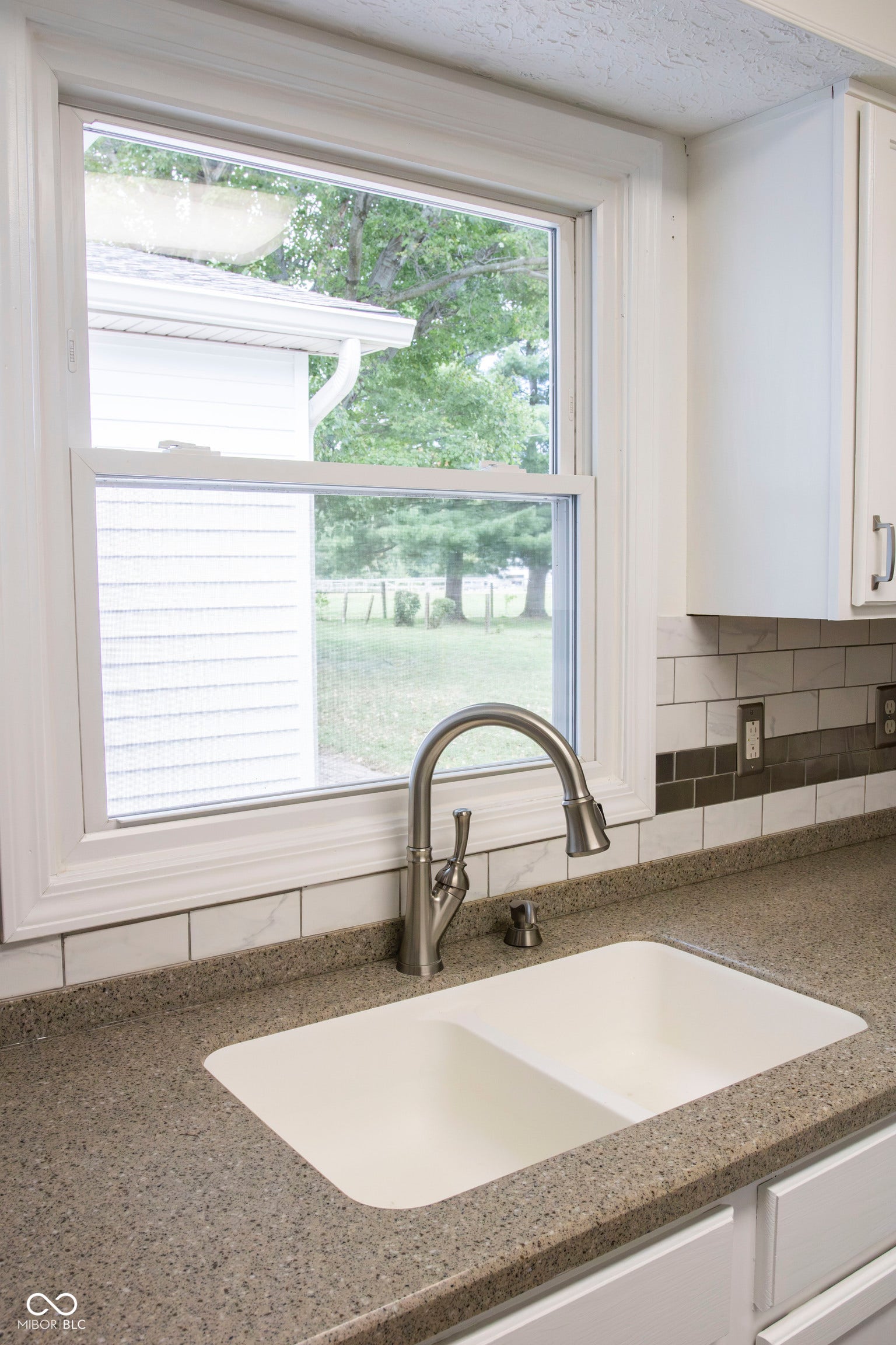 Dual-basin kitchen sink with a brushed nickel pull-down faucet, set into a speckled countertop