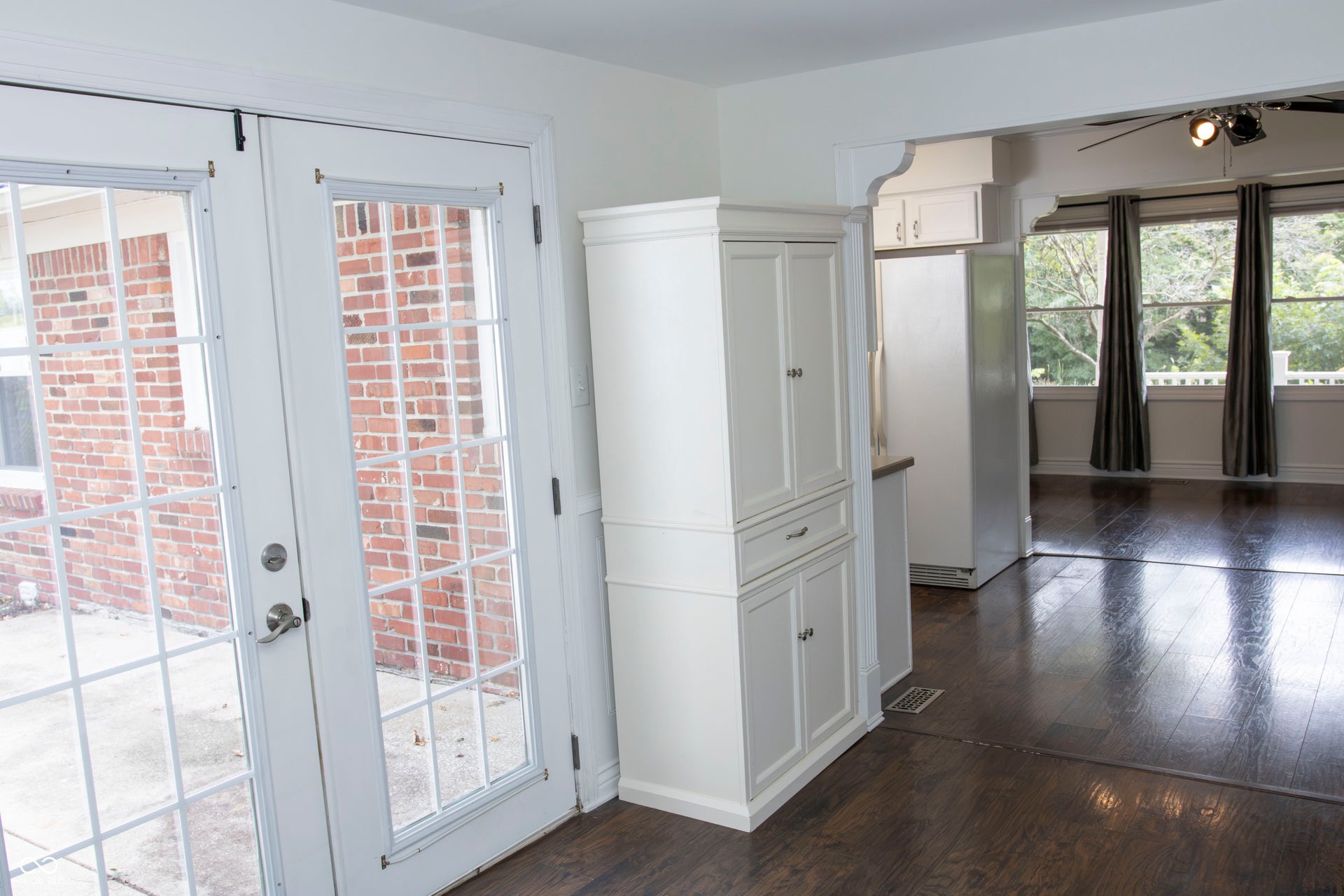 French doors with divided lites, dark wood-finish flooring, white built-in cabinetry, and a ceiling fan with integrated lighting