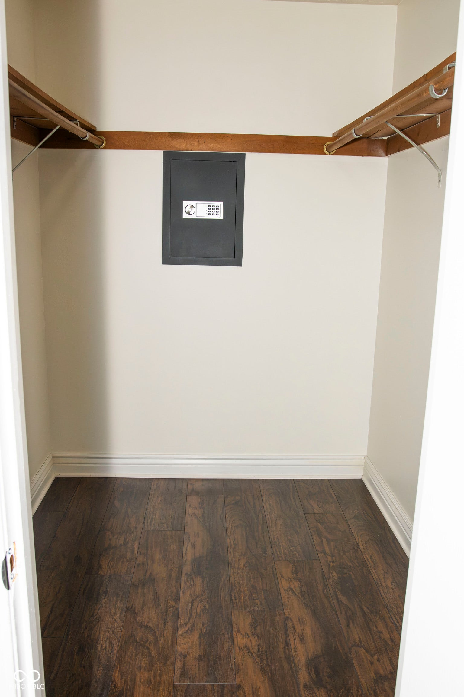 Built-in wall safe, wood-finish flooring, white trim, and light-colored walls