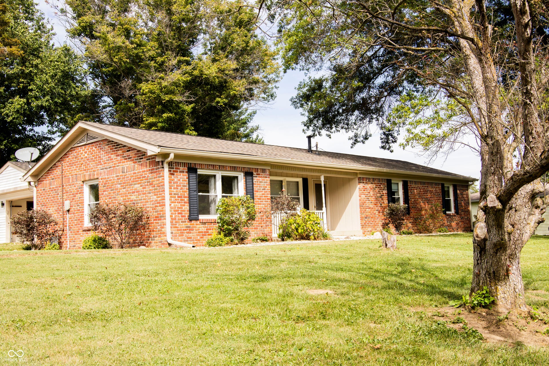 Brick exterior with white trim, front porch, and mature trees