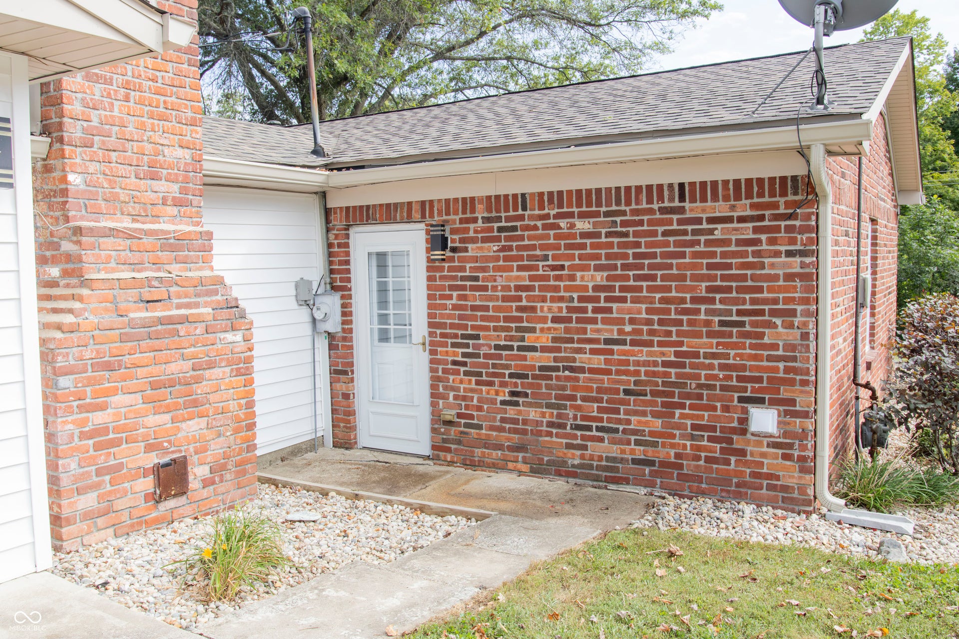 Brick exterior with white siding accents and a shingled roof