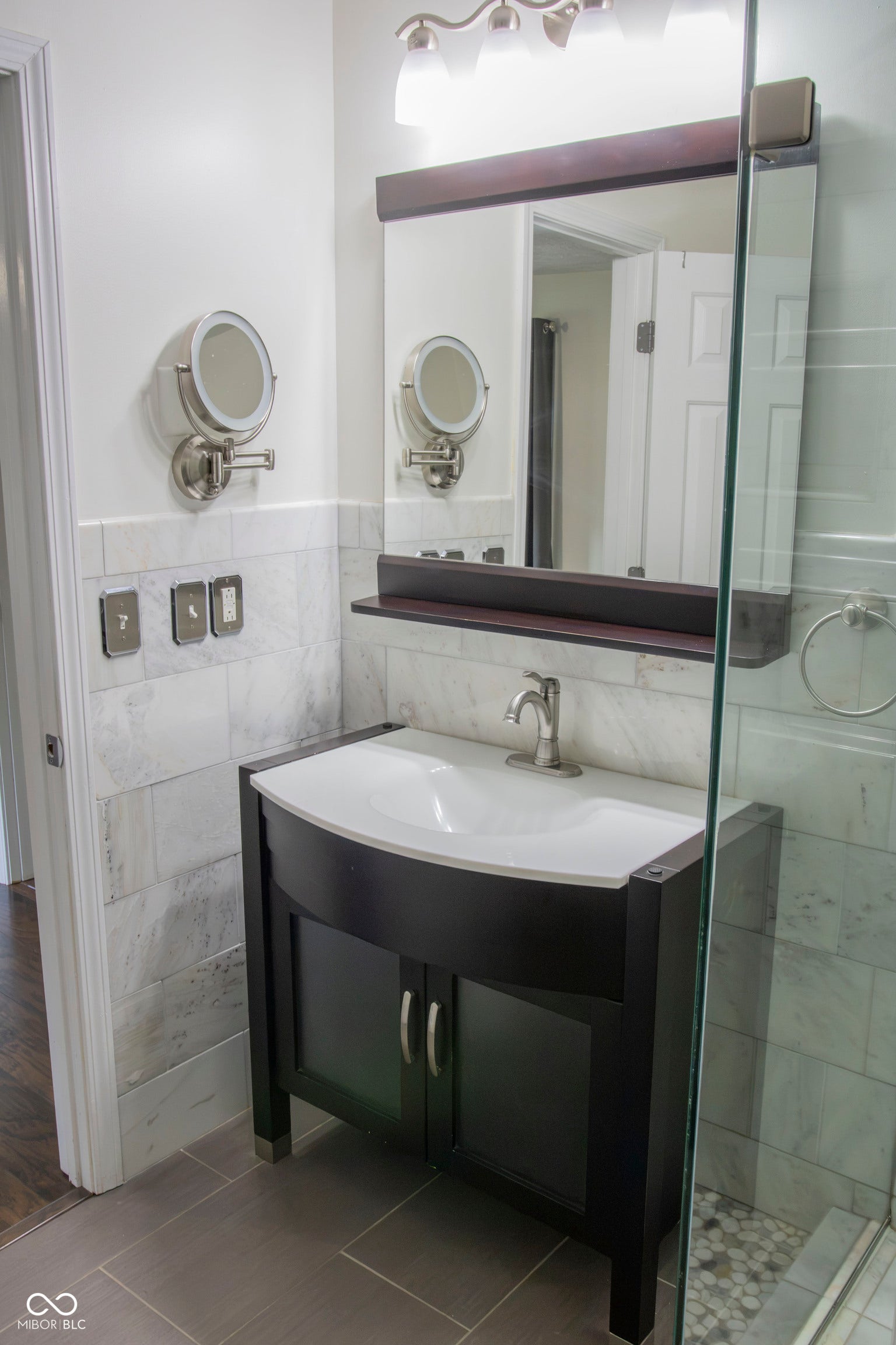 Vanity with curved basin, brushed nickel faucet, wood-framed mirror, and tiled walls