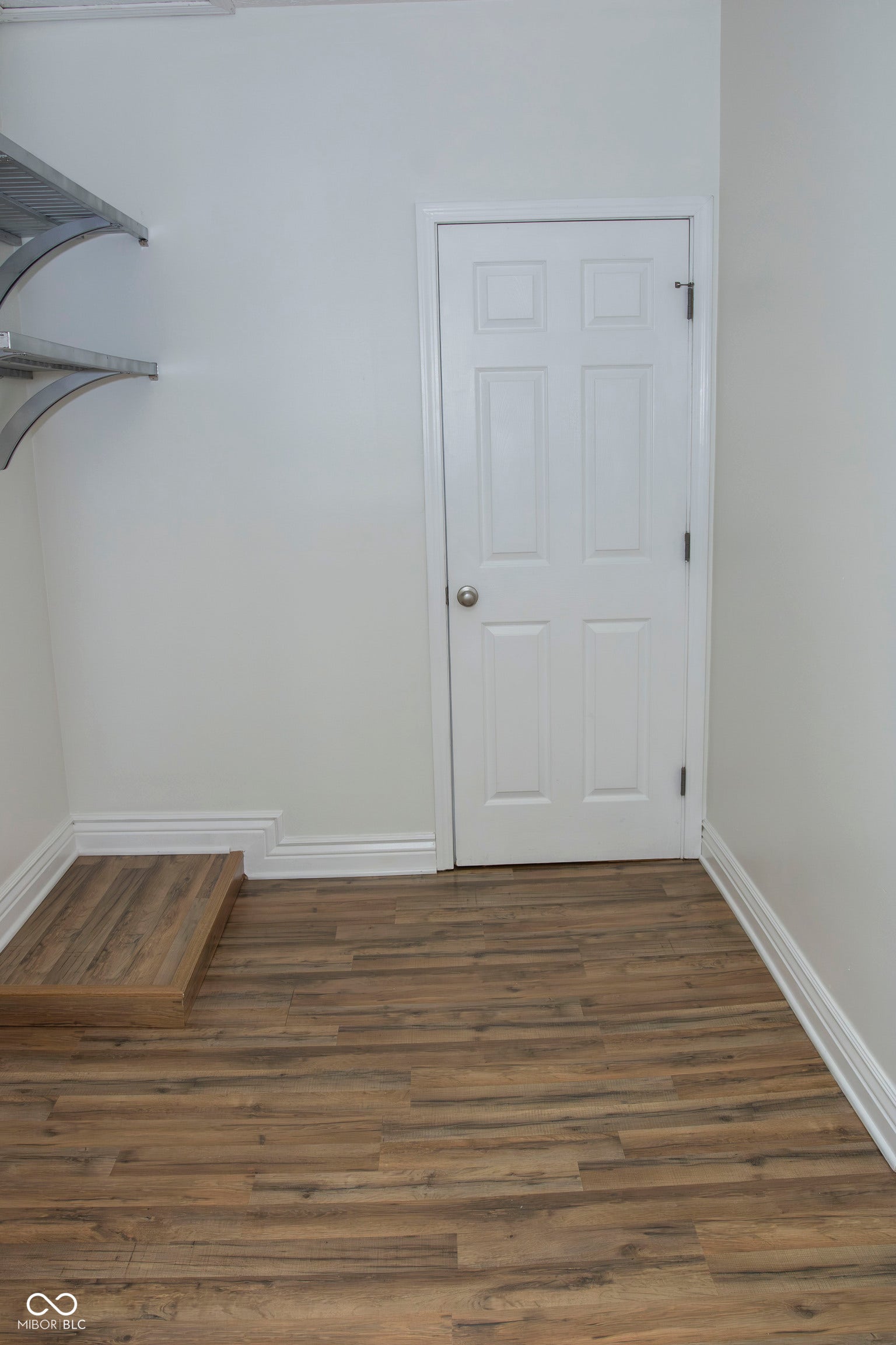 Wood-finish flooring, white paneled door, and built-in shelving