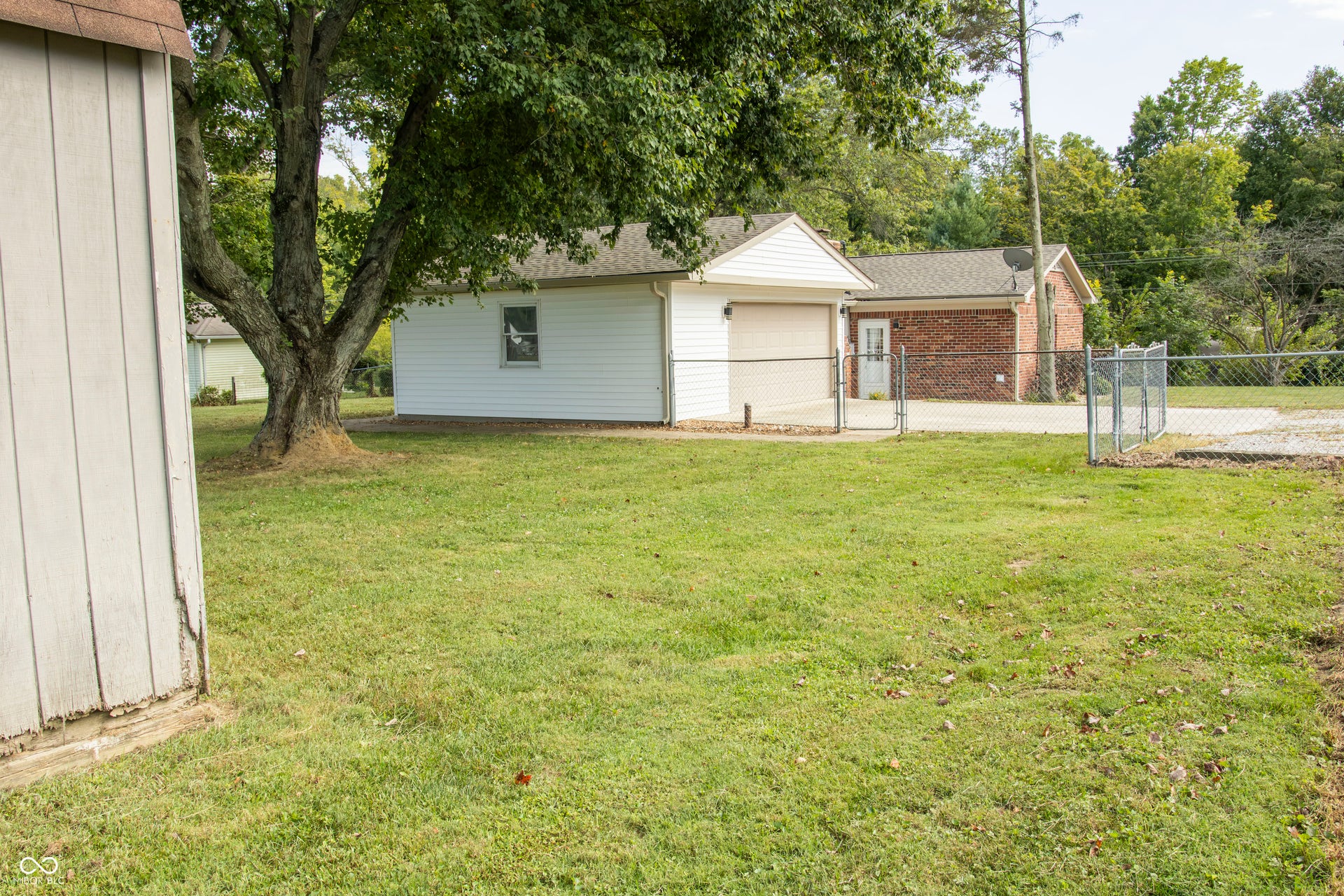 Detached garage with a single bay door, chain-link fencing, and a gravel driveway