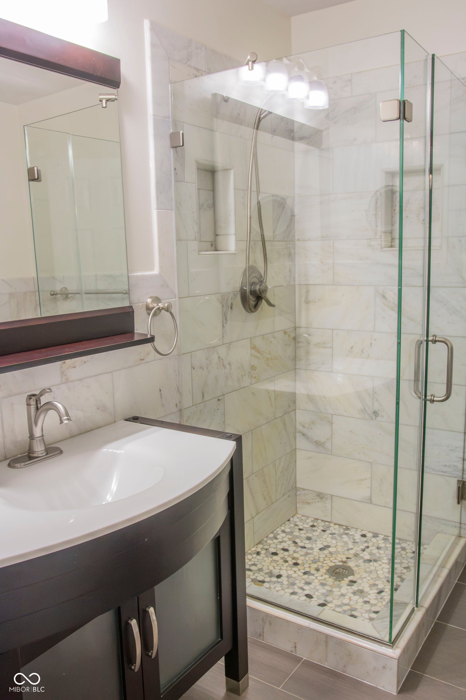 Glass-enclosed shower with pebble-tiled floor and a recessed niche
