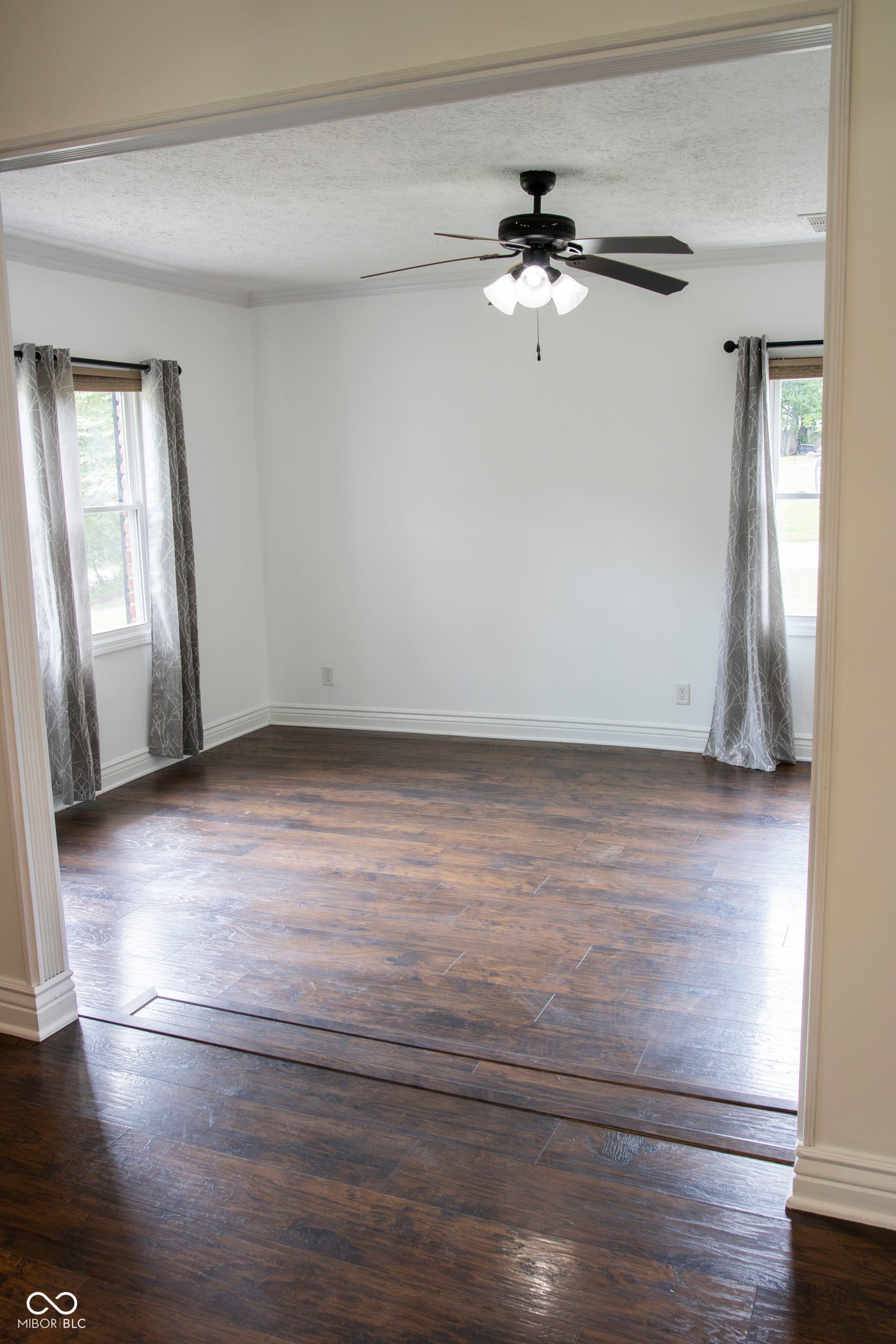 Spacious room featuring wood-finish flooring, white walls, and crown molding