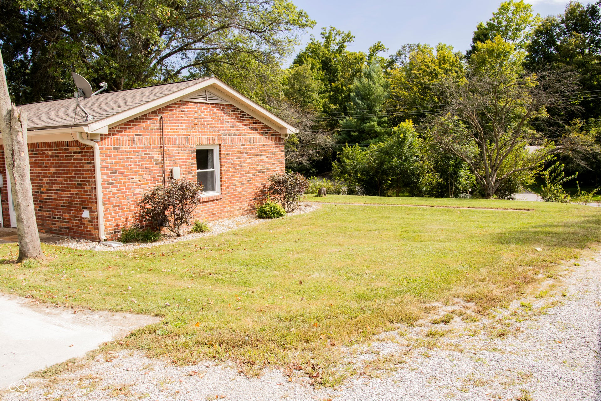 Brick exterior with white trim, a gabled roof, and a gravel driveway
