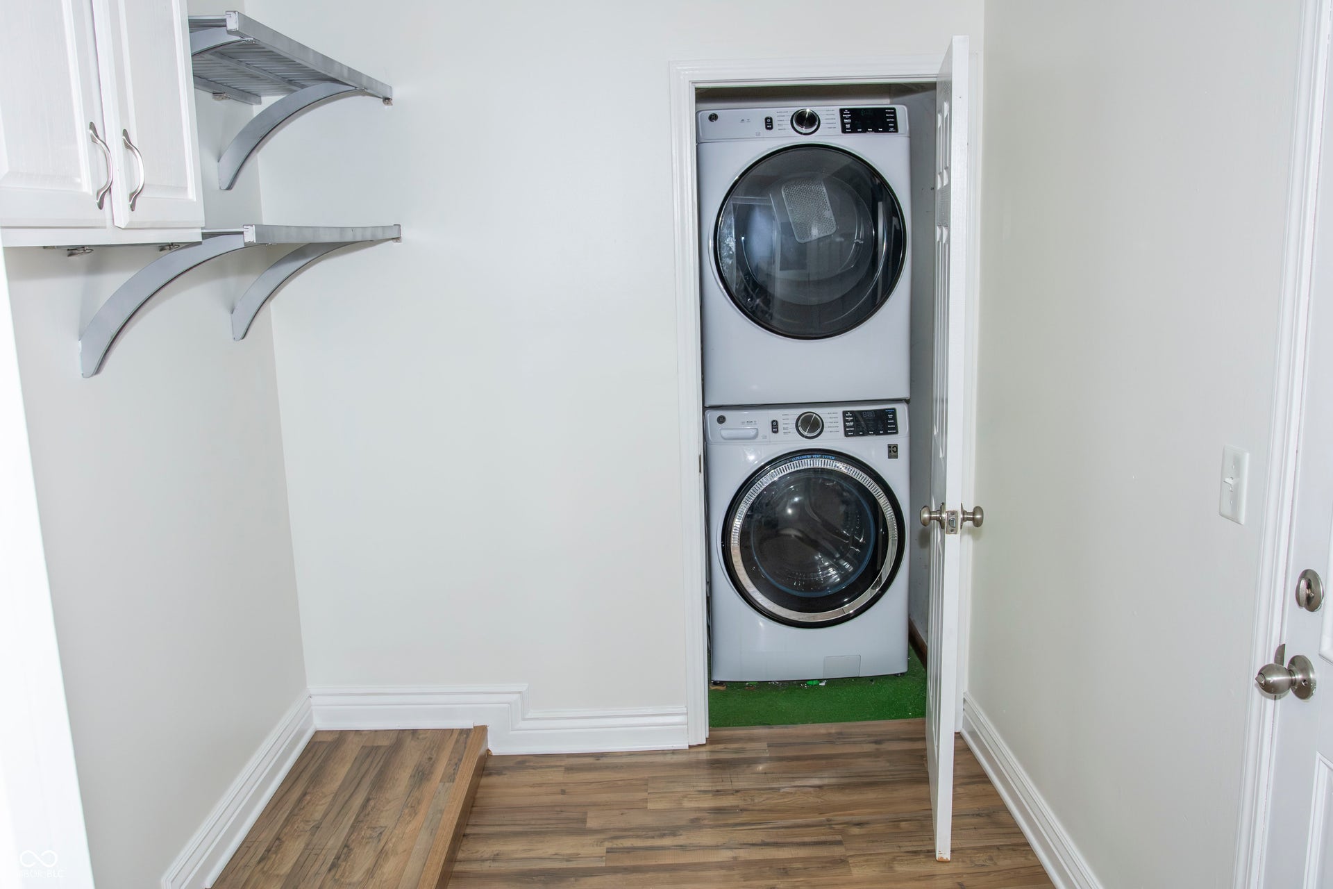Laundry area featuring wood-finish flooring, white walls, and built-in shelving