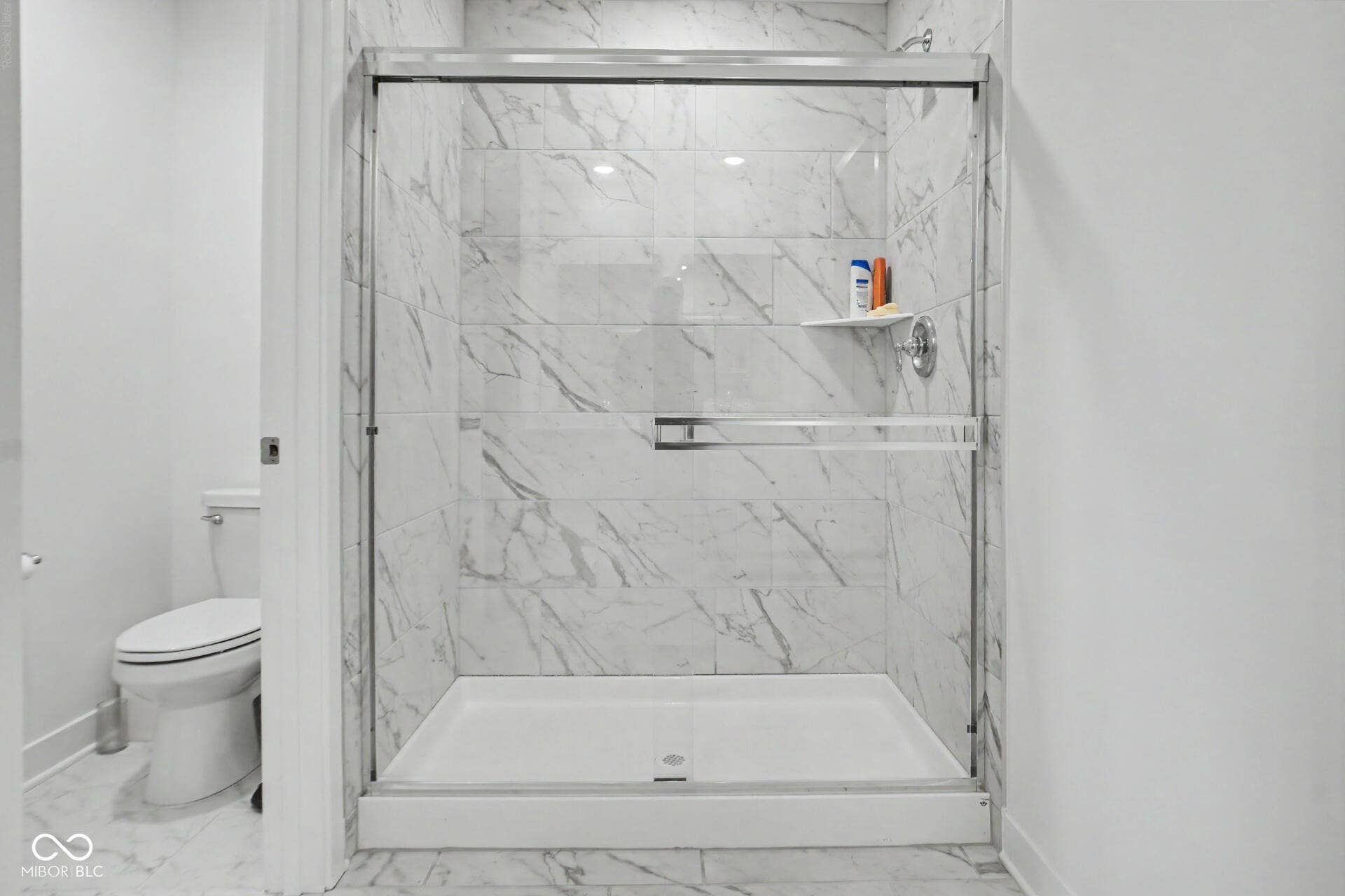4357 Red Pine Drive, Bargersville, IN 46106 Glass-enclosed shower with a polished chrome fixture, white marble-look tile, and a built-in shower shelf