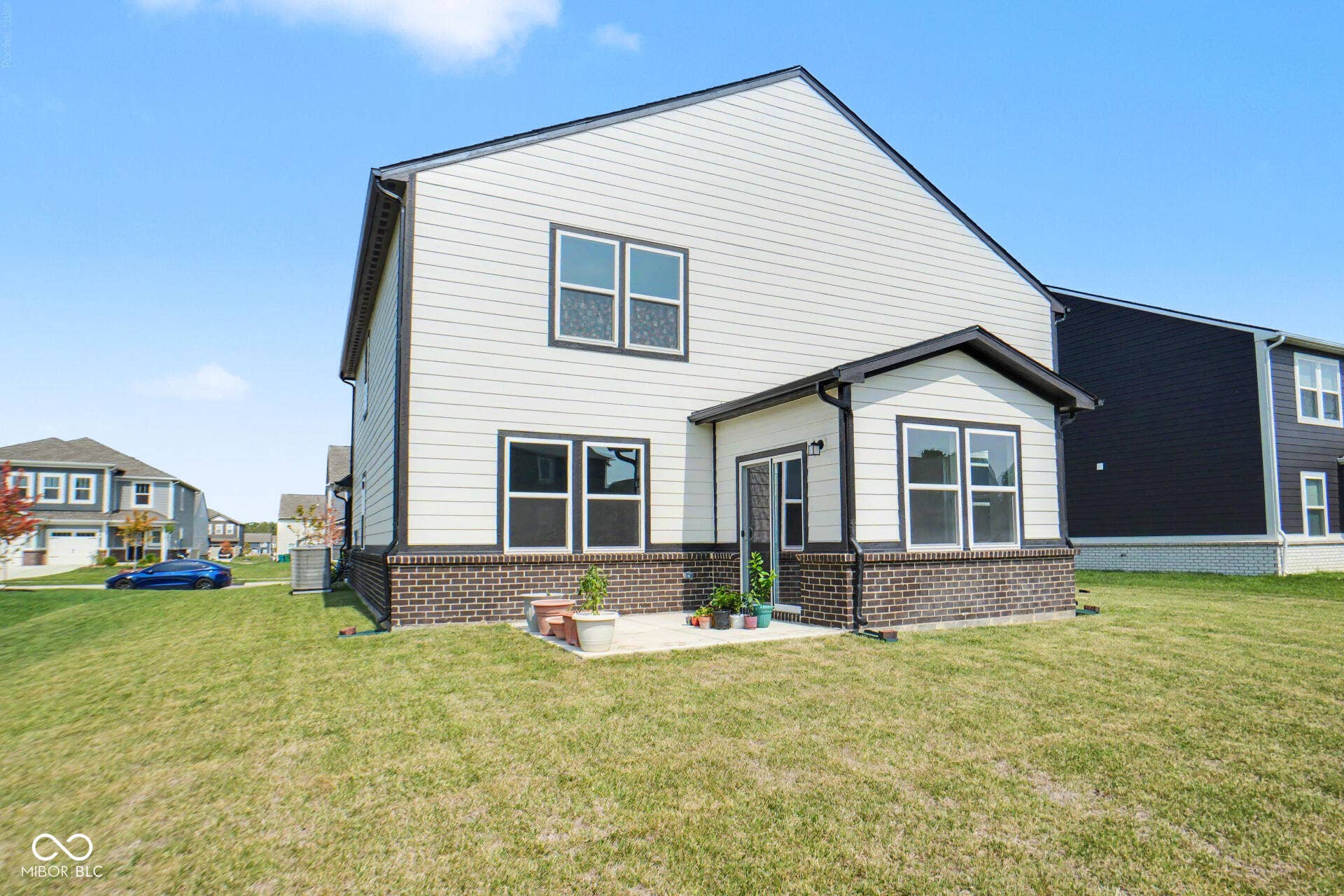 4357 Red Pine Drive, Bargersville, IN 46106 Exterior featuring light-colored siding, dark trim, a brick-front foundation, and an attached enclosed patio with multiple windows