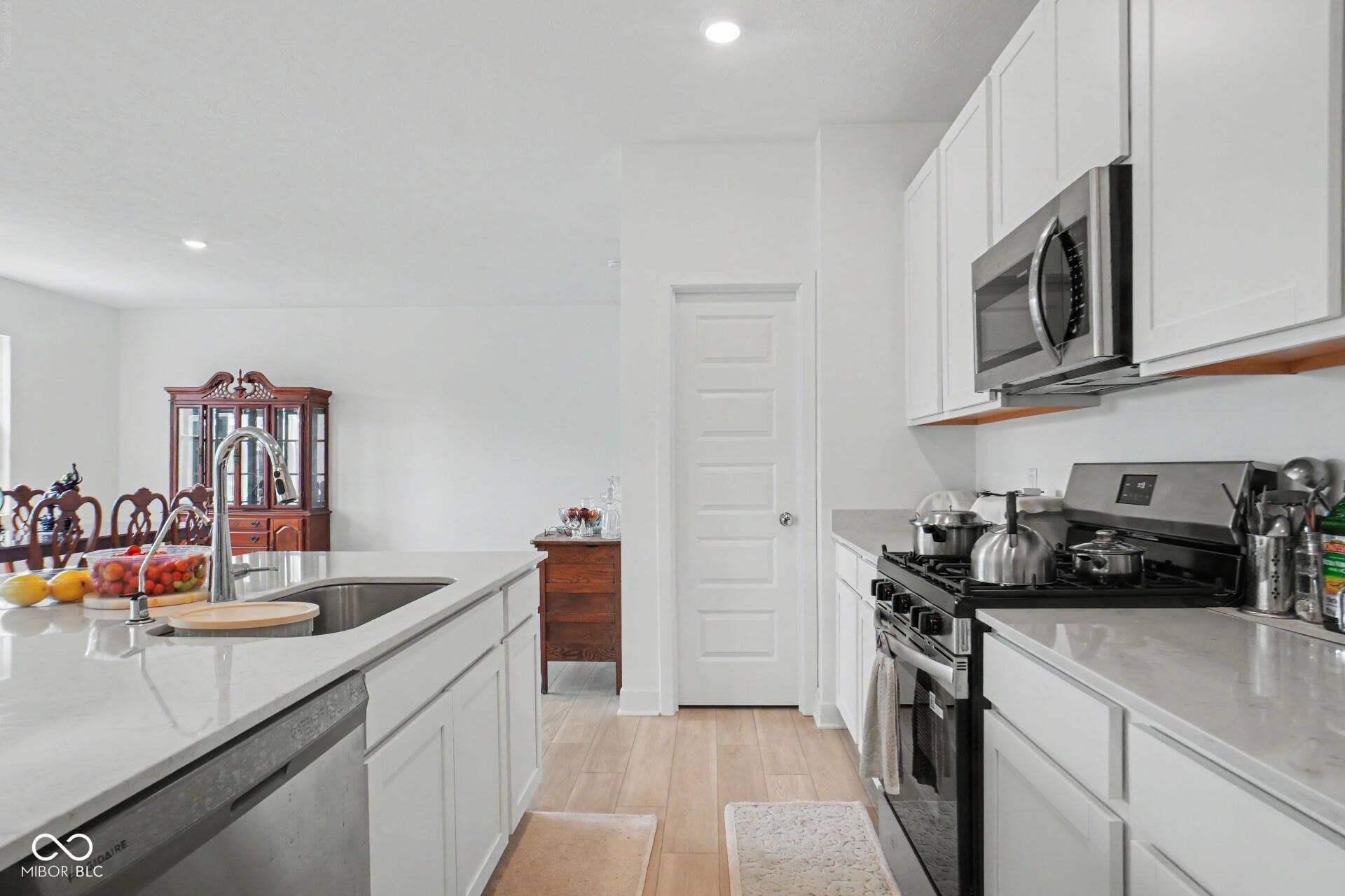 4357 Red Pine Drive, Bargersville, IN 46106 Modern kitchen featuring white cabinetry, stainless steel appliances including a gas range and built-in microwave, quartz countertops with waterfall edge detailing, and wood-finish flooring throughout