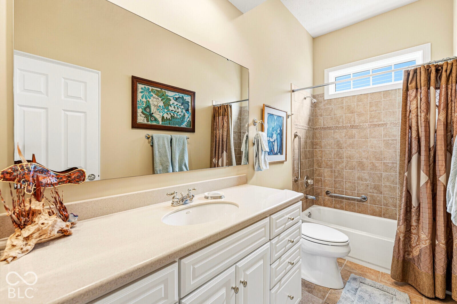 Bathroom featuring a spacious vanity with an integrated sink, white cabinetry, and a large wall-mounted mirror