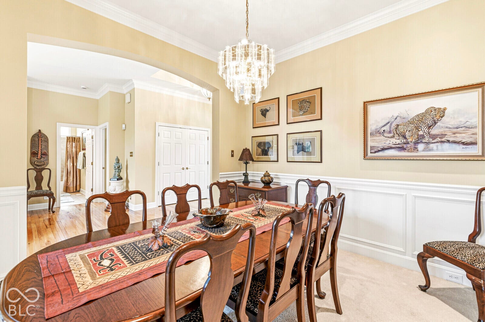 Arched doorway, crown molding, wainscoting, and a crystal chandelier