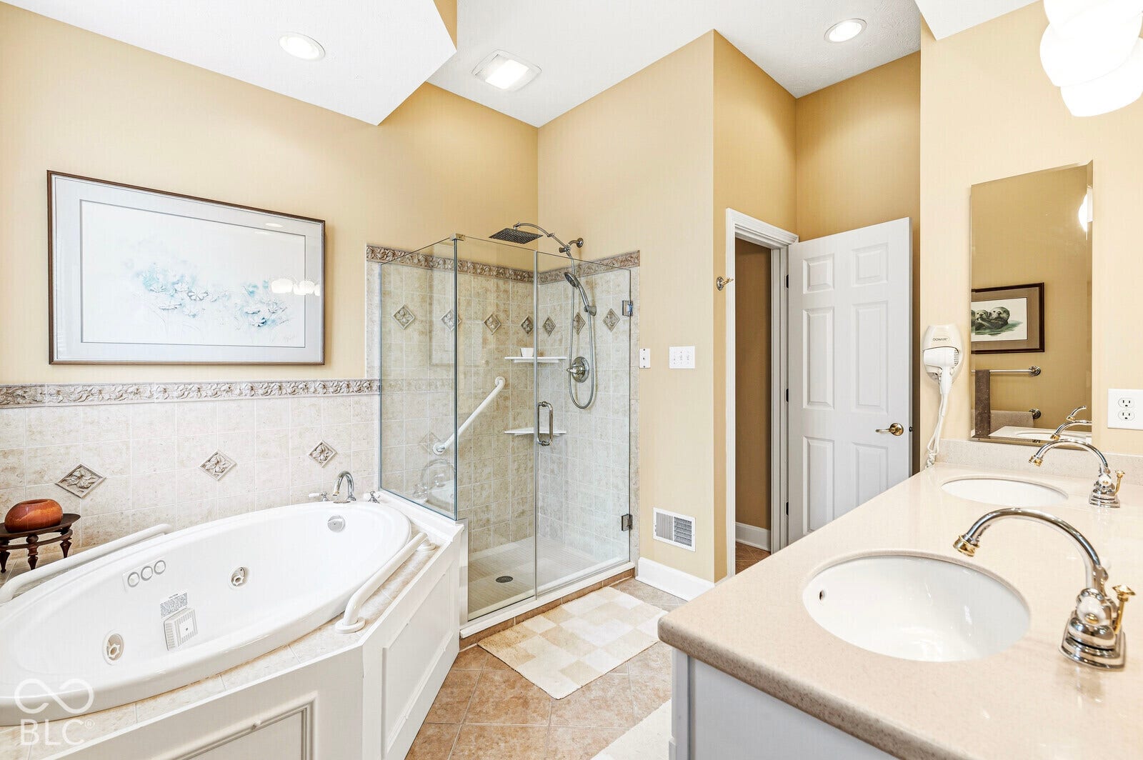 Dual vanity with undermount sinks, corner jetted tub, tiled shower with glass enclosure, and recessed lighting