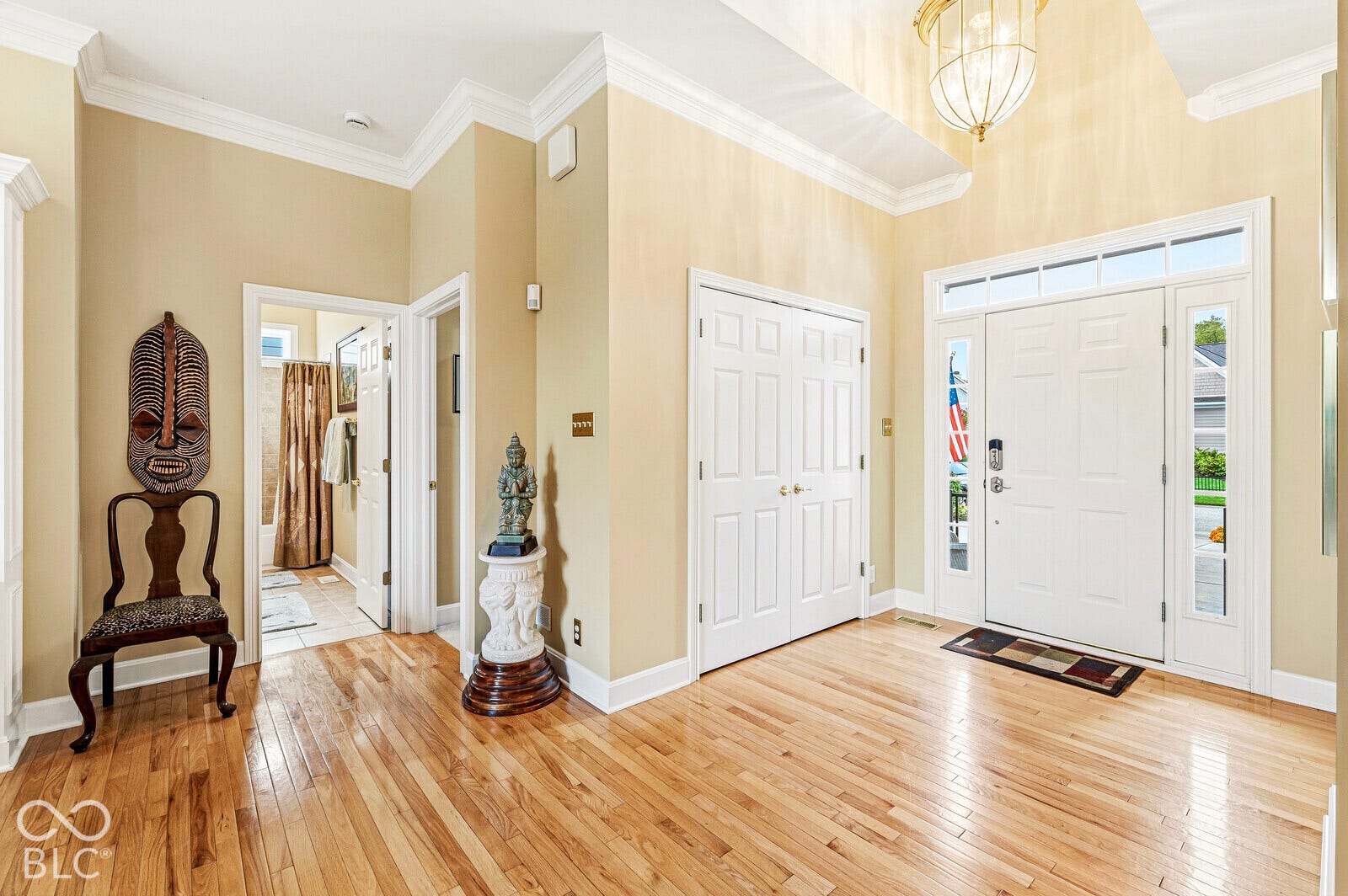 Foyer with wood-finish flooring, a vaulted ceiling, and crown molding