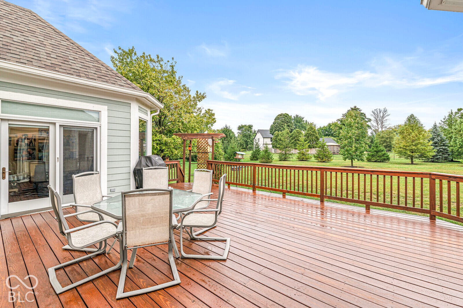 Expansive wood-finish deck with a wood railing and a sliding glass door