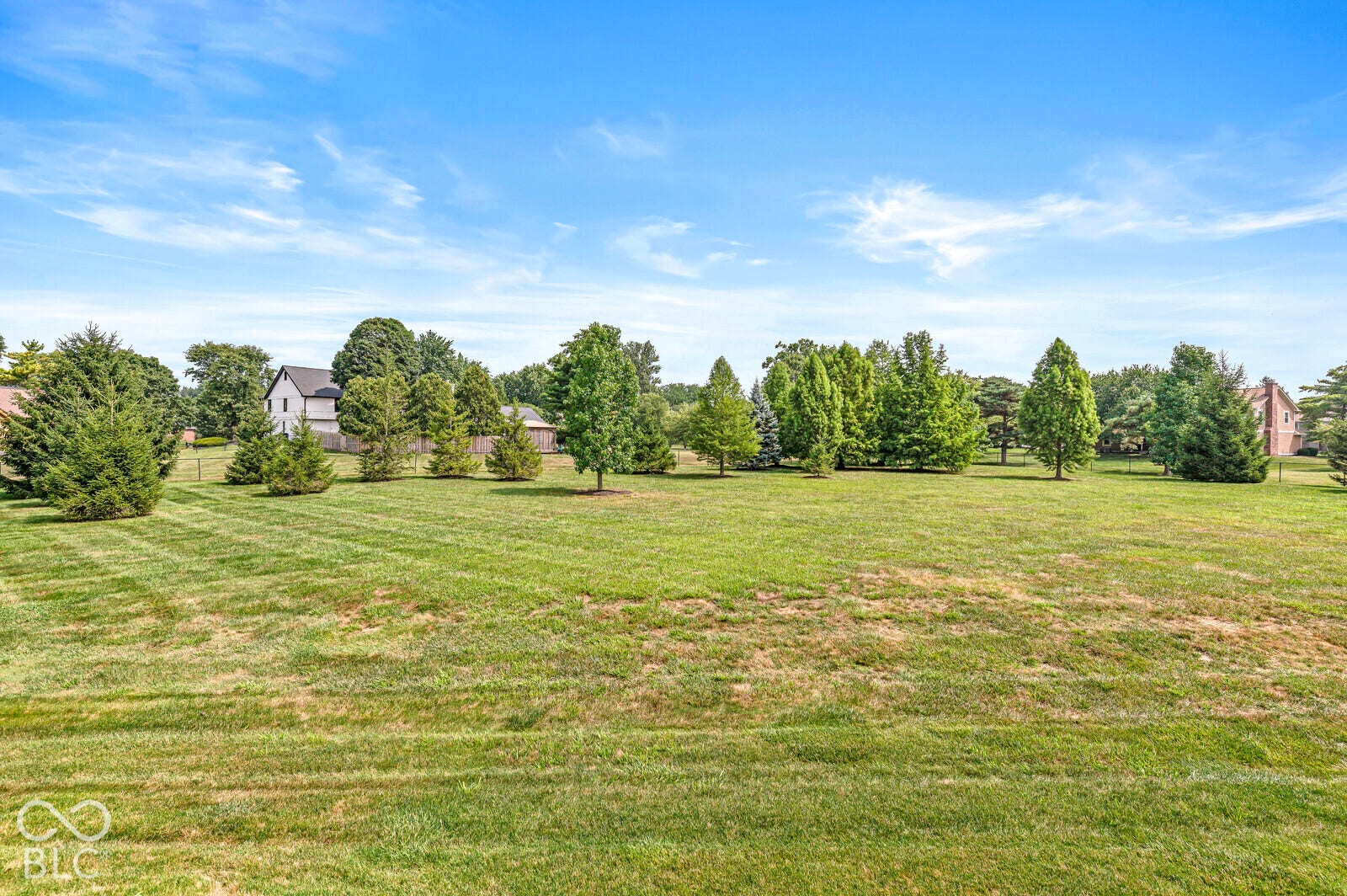 Expansive lawn area with surrounding mature trees and natural landscaping