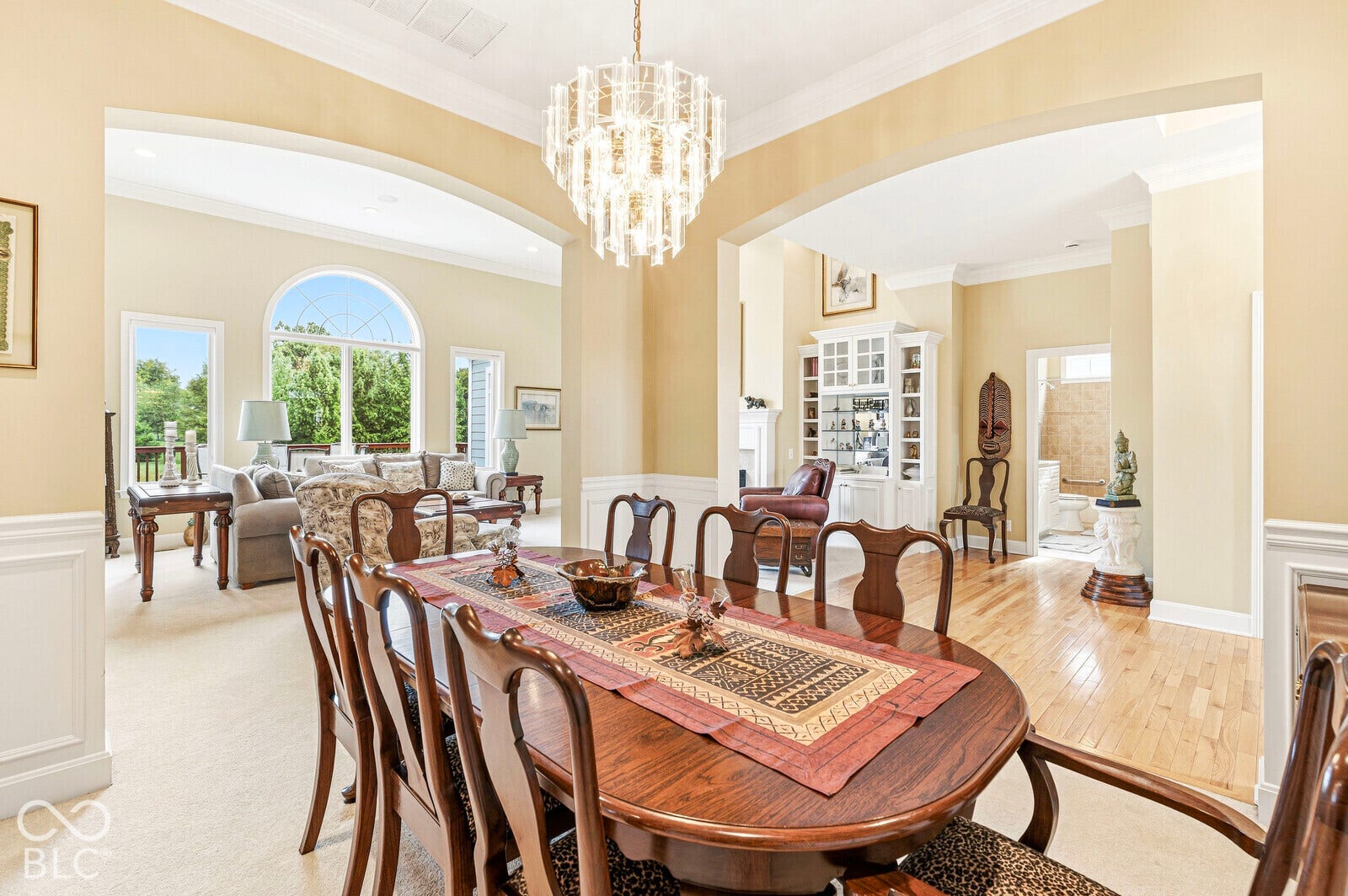 Spacious interior featuring arched doorways, a coffered ceiling, wainscoting, and wood-finish flooring