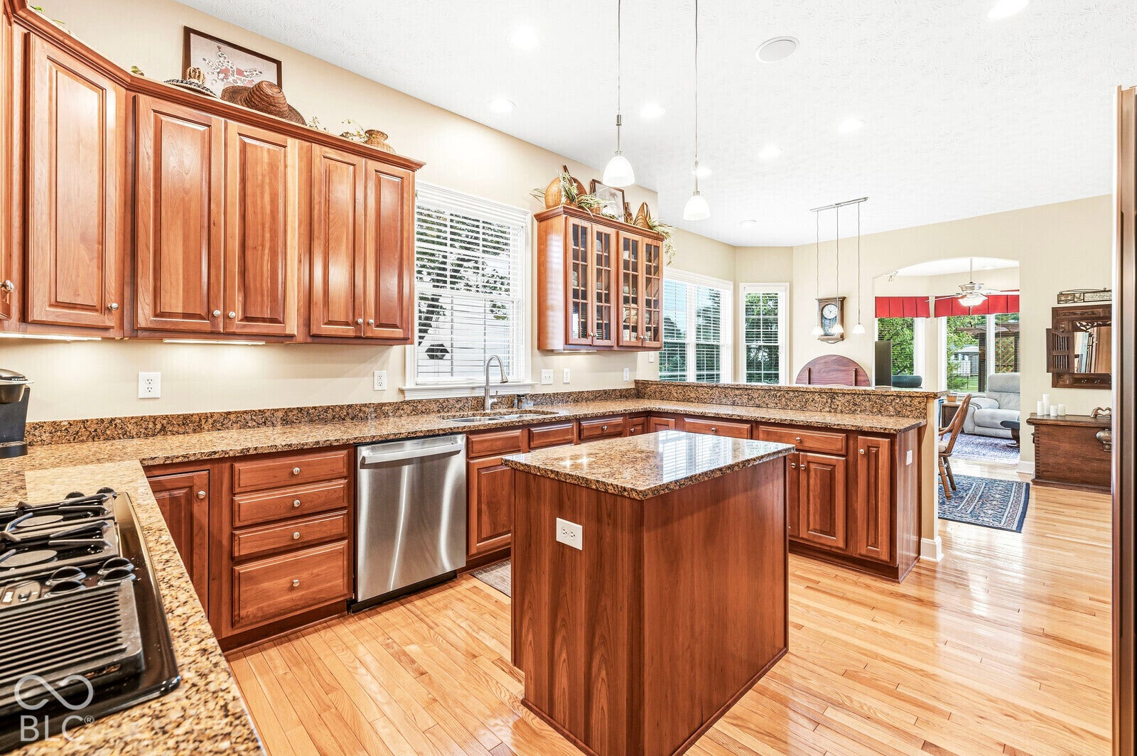Wood-finish flooring, wood cabinetry, stone countertops, stainless steel appliances, and recessed lighting