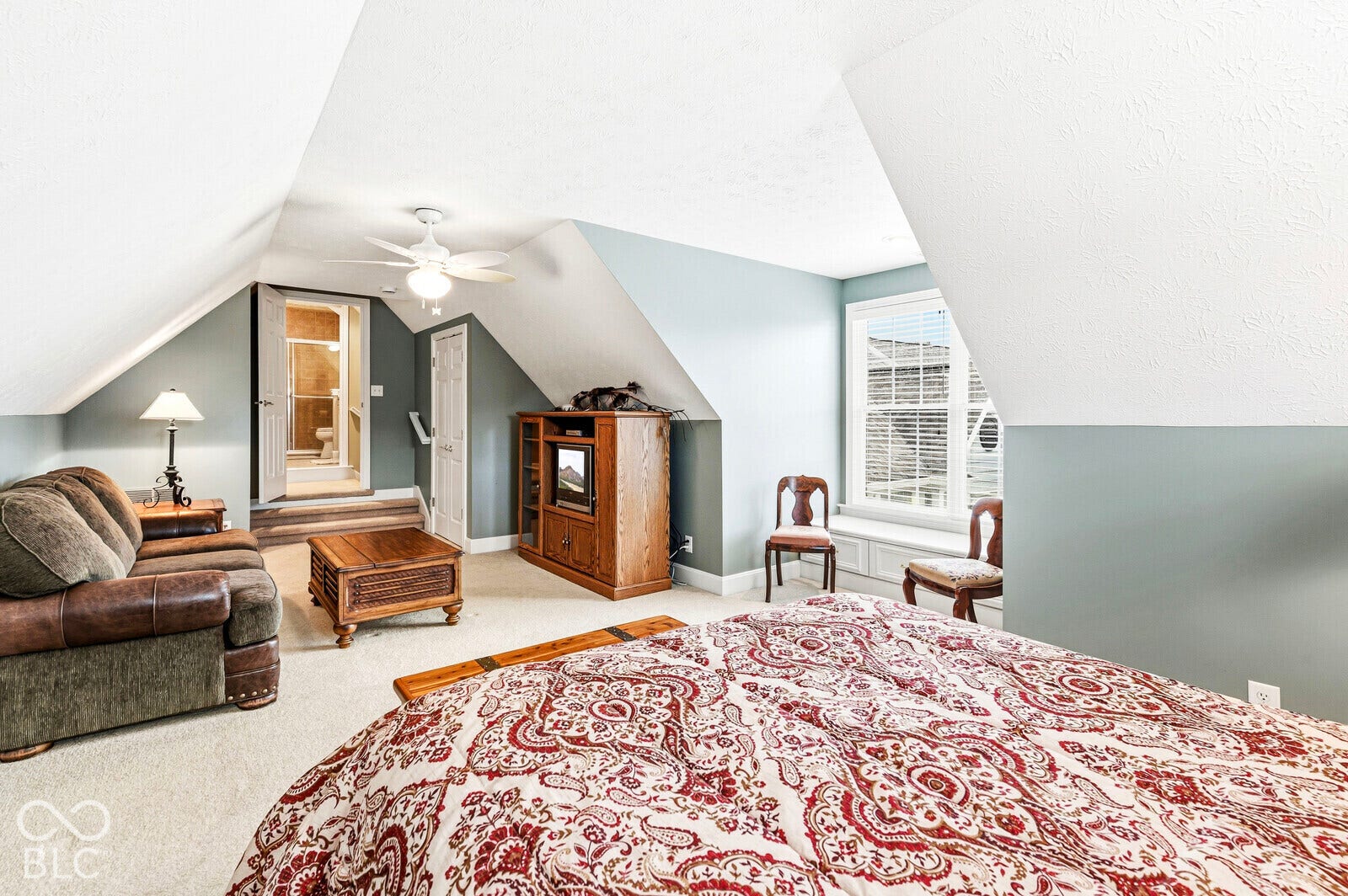 Sloped ceilings with recessed wall sections, ceiling fan, and carpeted flooring