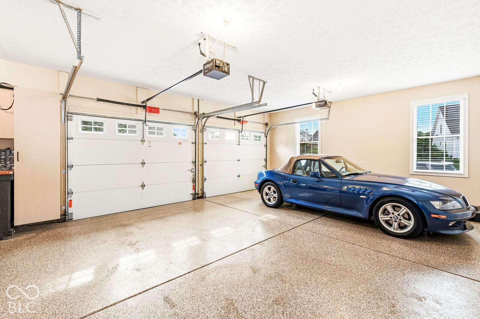 Two-car garage featuring segmented overhead doors with clear window panels, a durable epoxy floor finish, and integrated windows providing natural light