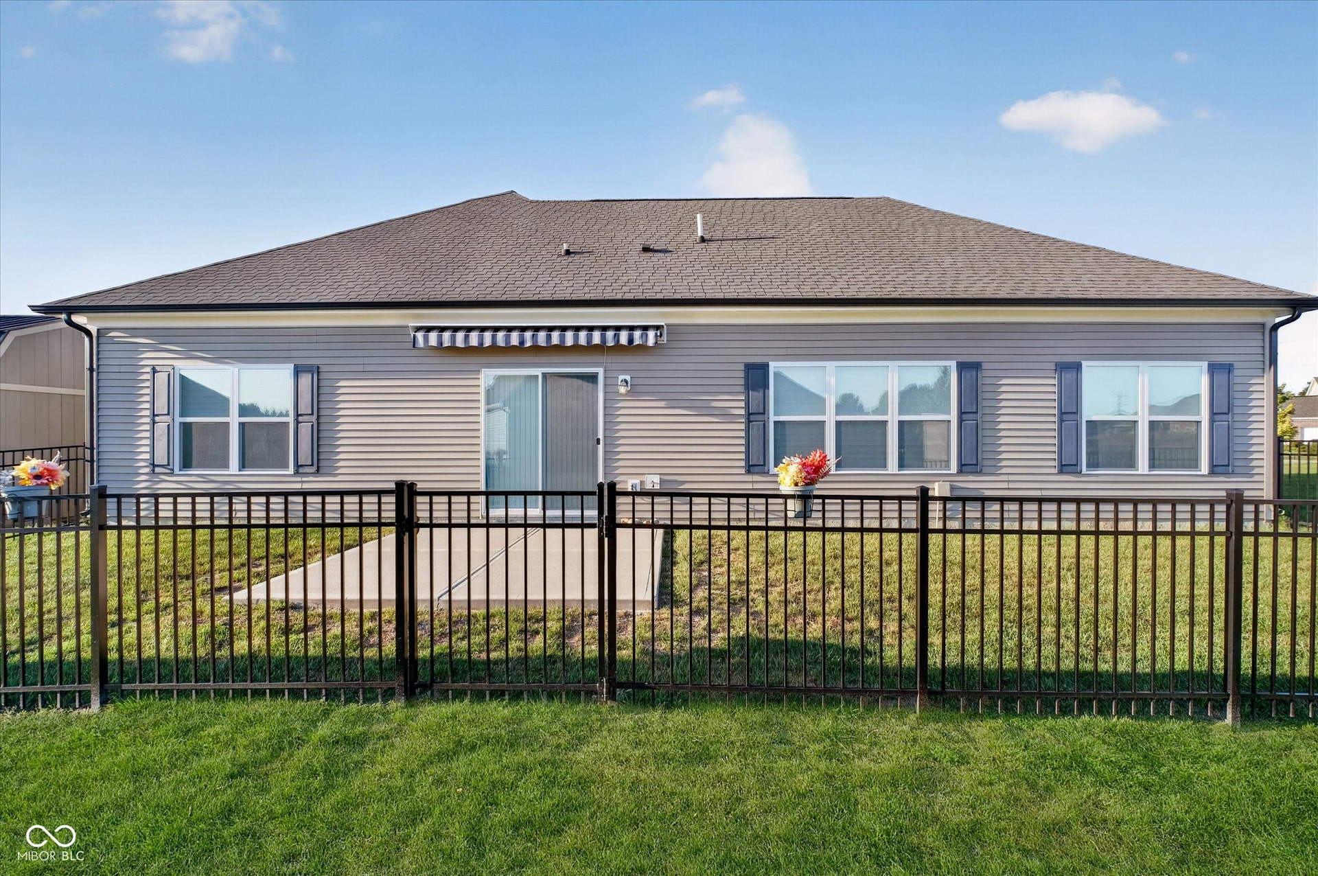 Rear exterior with vinyl siding, a shingled roof, multiple windows with shutters, and a sliding glass door