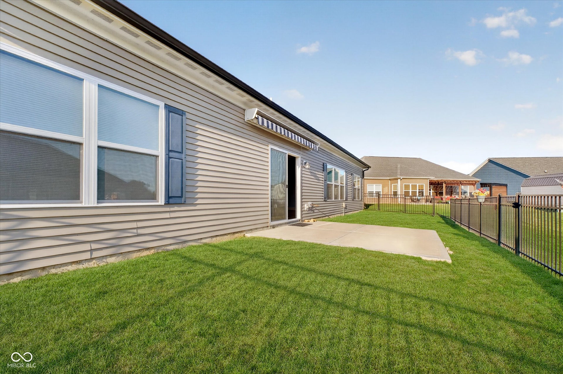 Siding exterior with decorative shutters, sliding glass door, concrete patio, and a fenced yard