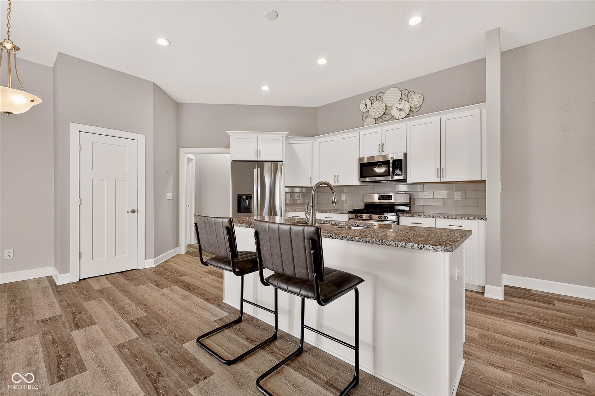 Modern kitchen featuring white cabinetry, stainless steel appliances, a center island with bar seating, and wood-finish flooring