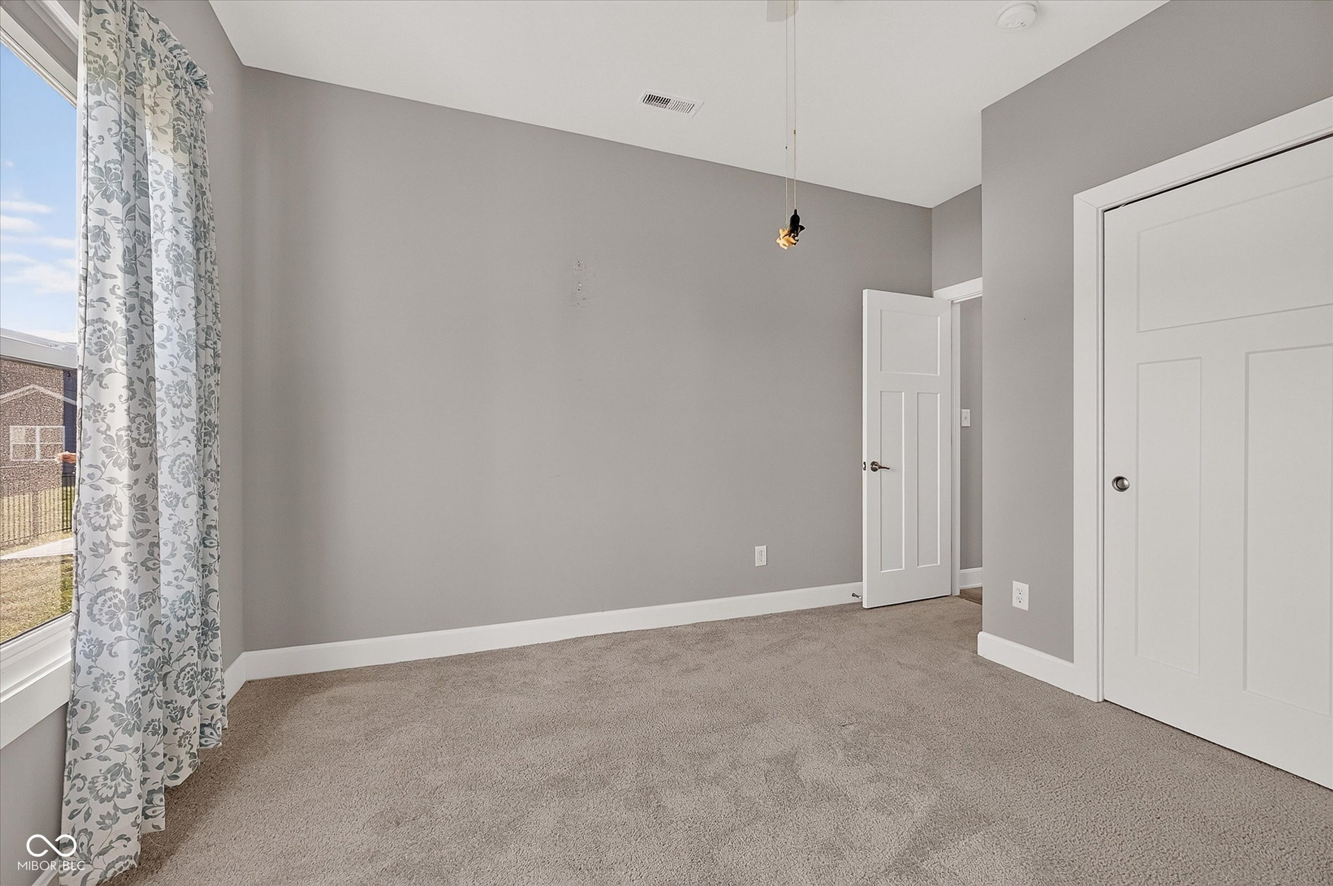 Expansive carpeted flooring, neutral wall tones, white trim, and a contemporary pendant light fixture