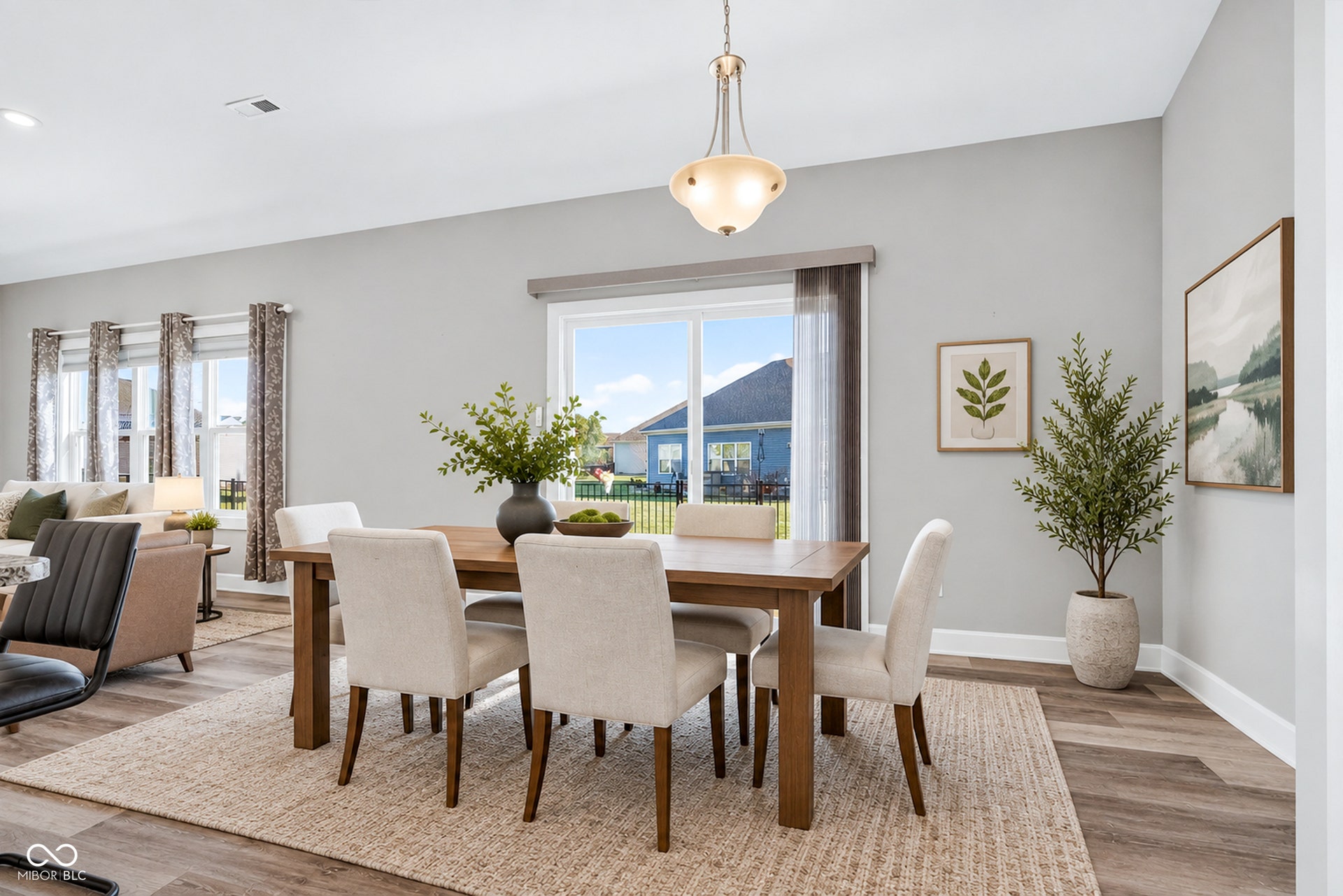 Virtually Altered - Open-concept dining area with wood-finish flooring, a contemporary chandelier, and direct access to the exterior through a glass slider