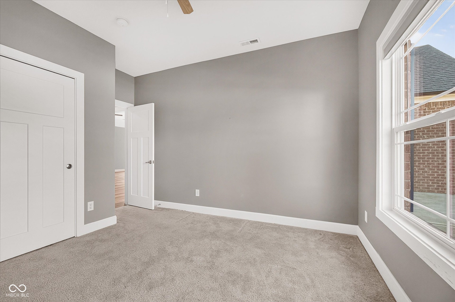Carpeted flooring, neutral wall color, white trim, ceiling fan, and large window