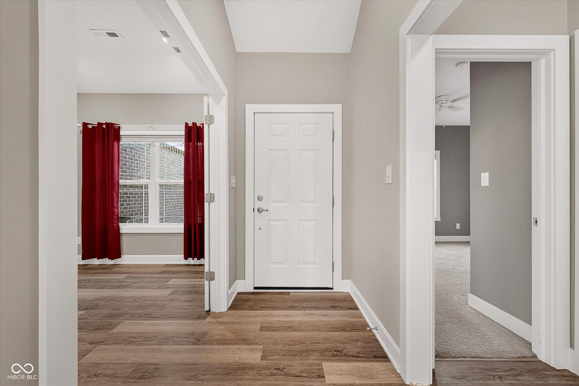Wood-finish flooring throughout, white paneled door, light gray wall paint, recessed lighting, and white trim